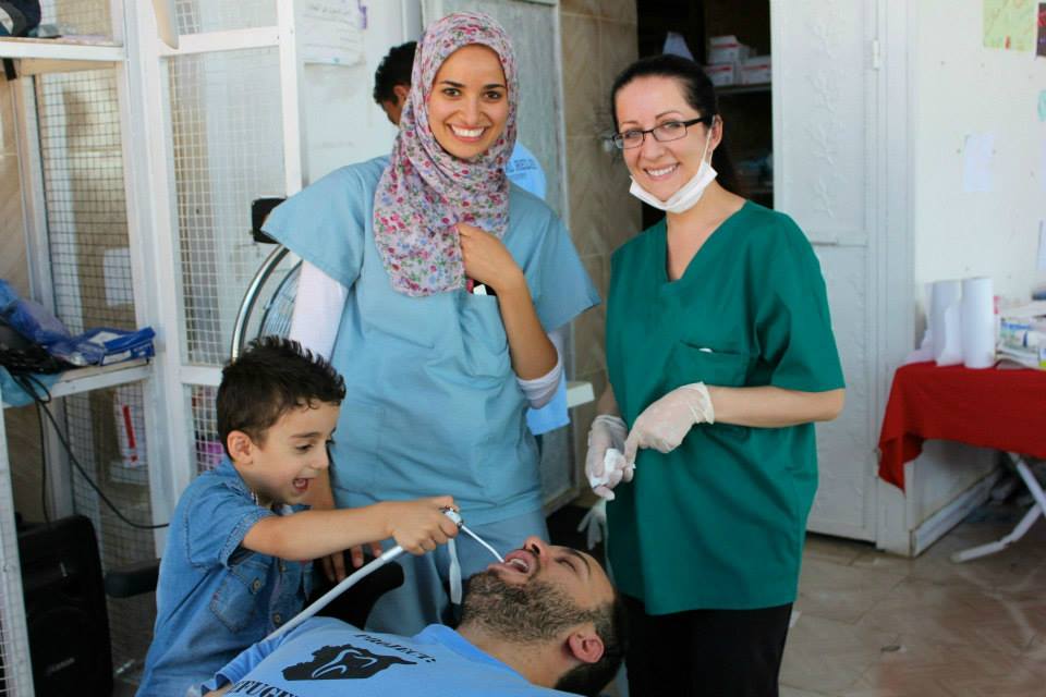 Mohammad, a boy Farris Barakat (seated) helped in the Project Refugee Smiles clinic, says he wants to be a doctor when he grows up. Standing next to him are Dr. Sara Aref of Cleveland (center) and Alena Advic of Seattle. Mohammad, a boy Farris Barakat (seated) helped in the Project Refugee Smiles clinic, says he wants to be a doctor when he grows up. Standing next to him are Dr. Sara Aref of Cleveland (center) and Alena Advic of Seattle.