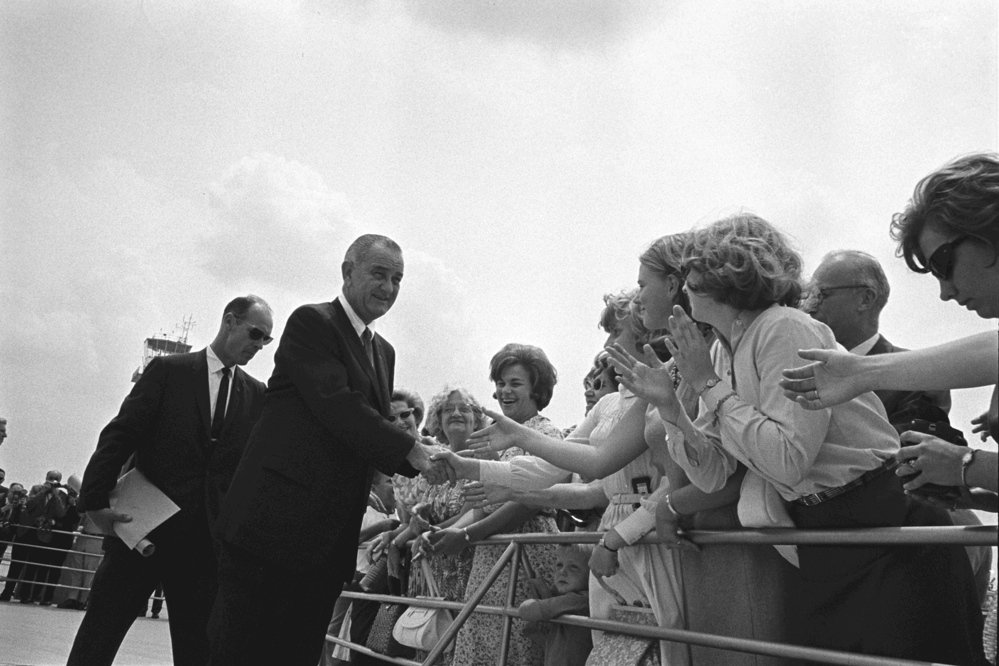 President Lyndon B. Johnson greets crowds, USSS Agent Rufus Youngblood is behind him. President Lyndon B. Johnson greets crowds, USSS Agent Rufus Youngblood is behind him.