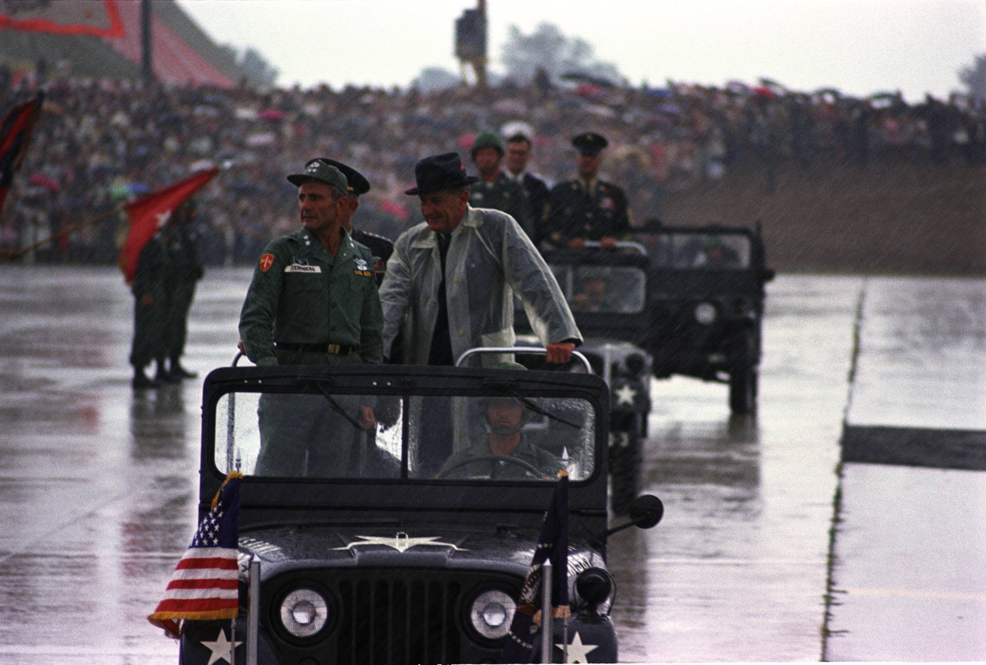 Standing in a jeep during a rainstorm (L-R:) Maj. Gen. Ben Sternberg, Pres. Lyndon B. Johnson Standing in a jeep during a rainstorm (L-R:) Maj. Gen. Ben Sternberg, Pres. Lyndon B. Johnson