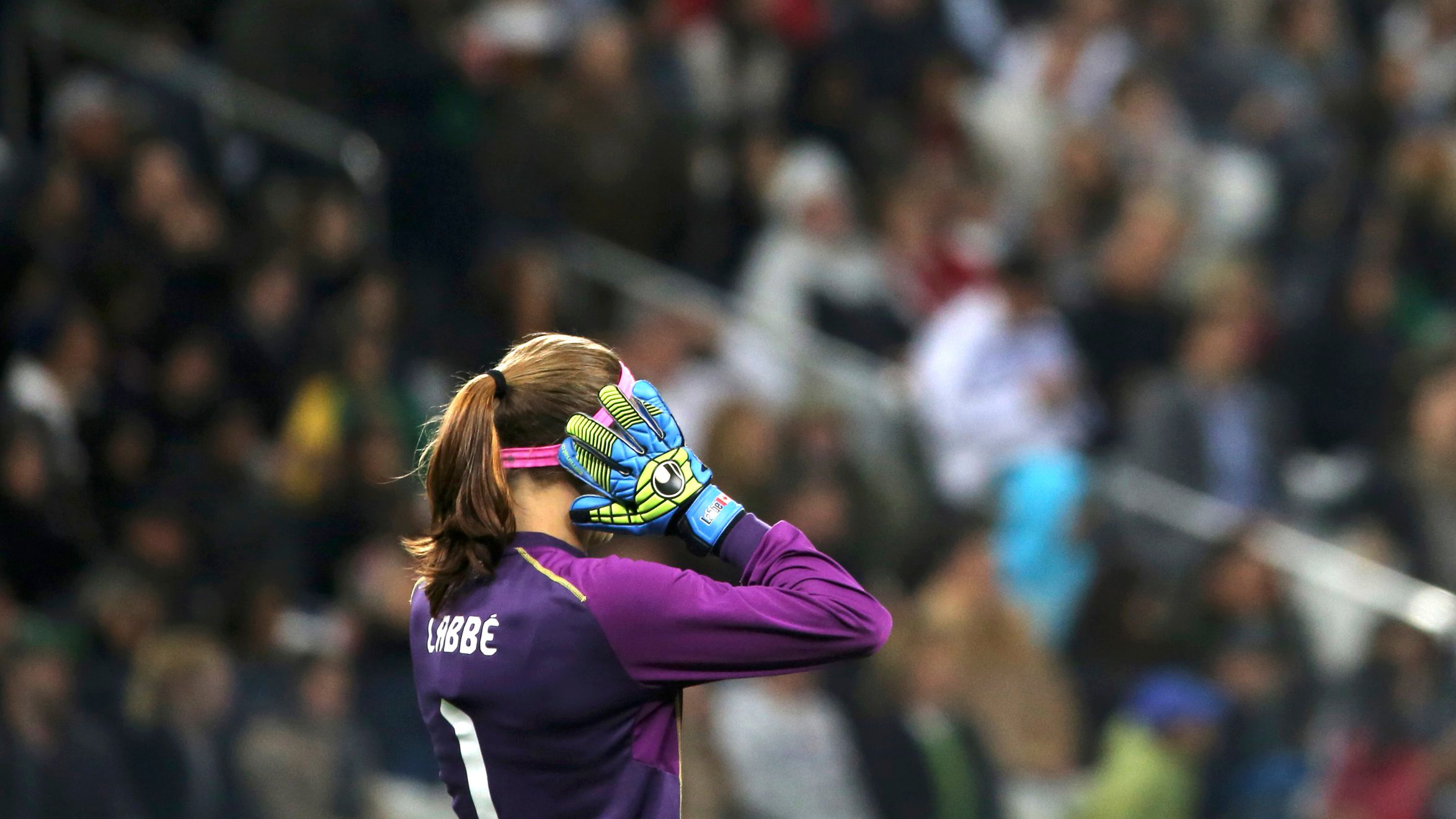 Goalkeeper Stephanie Labbe of Canada in a match against France at the 2016 Rio Olympics. Stephanie Labbe raises her hands while standing in goal.