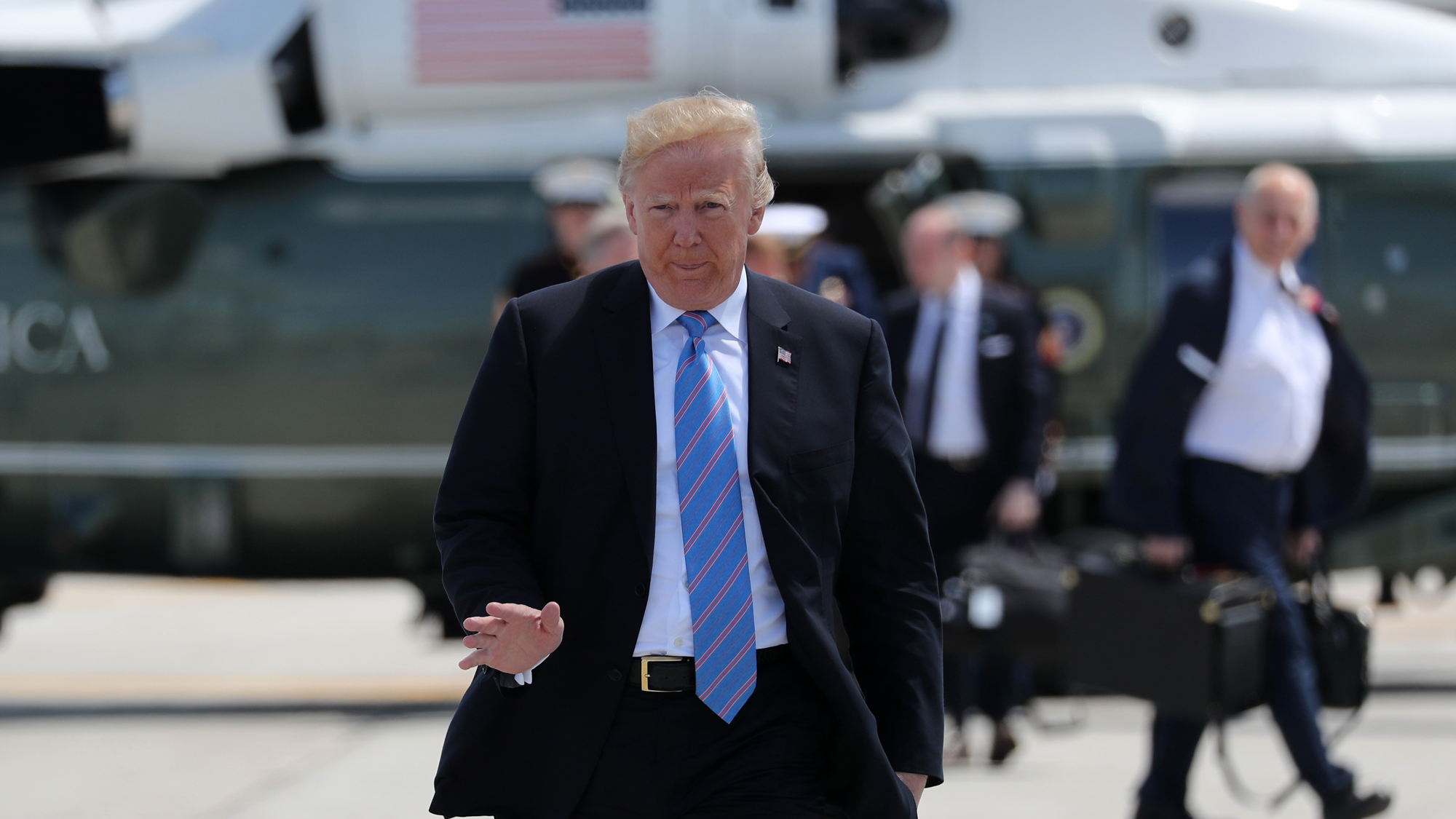 US President Donald Trump waves as he arrives to board Air Force One to depart for travel to Singapore. US President Donald Trump, wearing a suit and blue-stripped tie, waves as he arrives to board Air Force One.