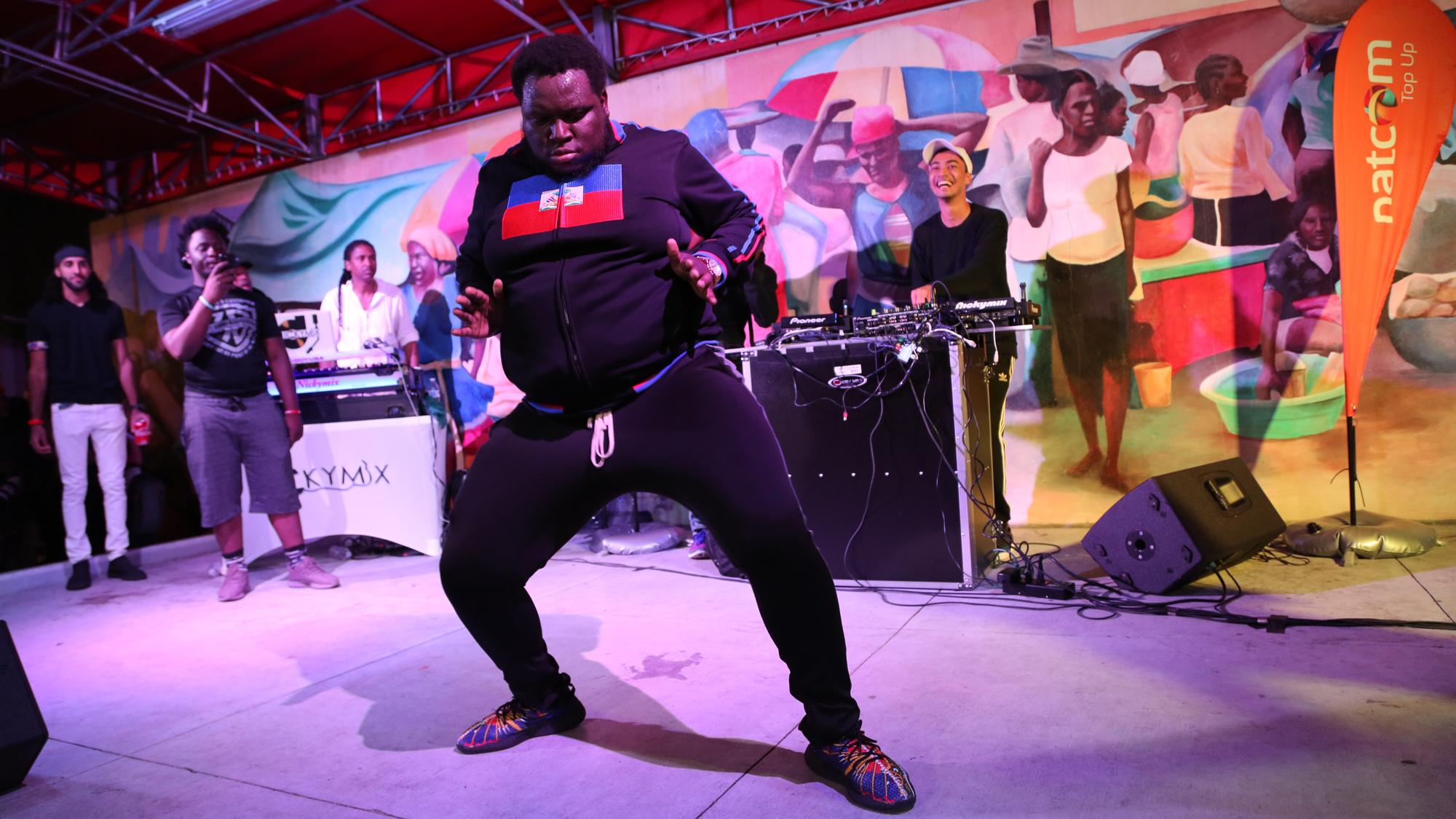 A fan joins DJ Michael Brun on stage at the Bayo Block Party in Little Haiti Cultural Complex, Miami, Flordia on March 23, 2018. Brun says he’s taking the party on the road to change how people in the US see Haiti. A fan dressed in a sweatshirt with the Haitian flag on it, joins DJ Michael Brun on stage at the Bayo Block Party in Miami, Flordia.
