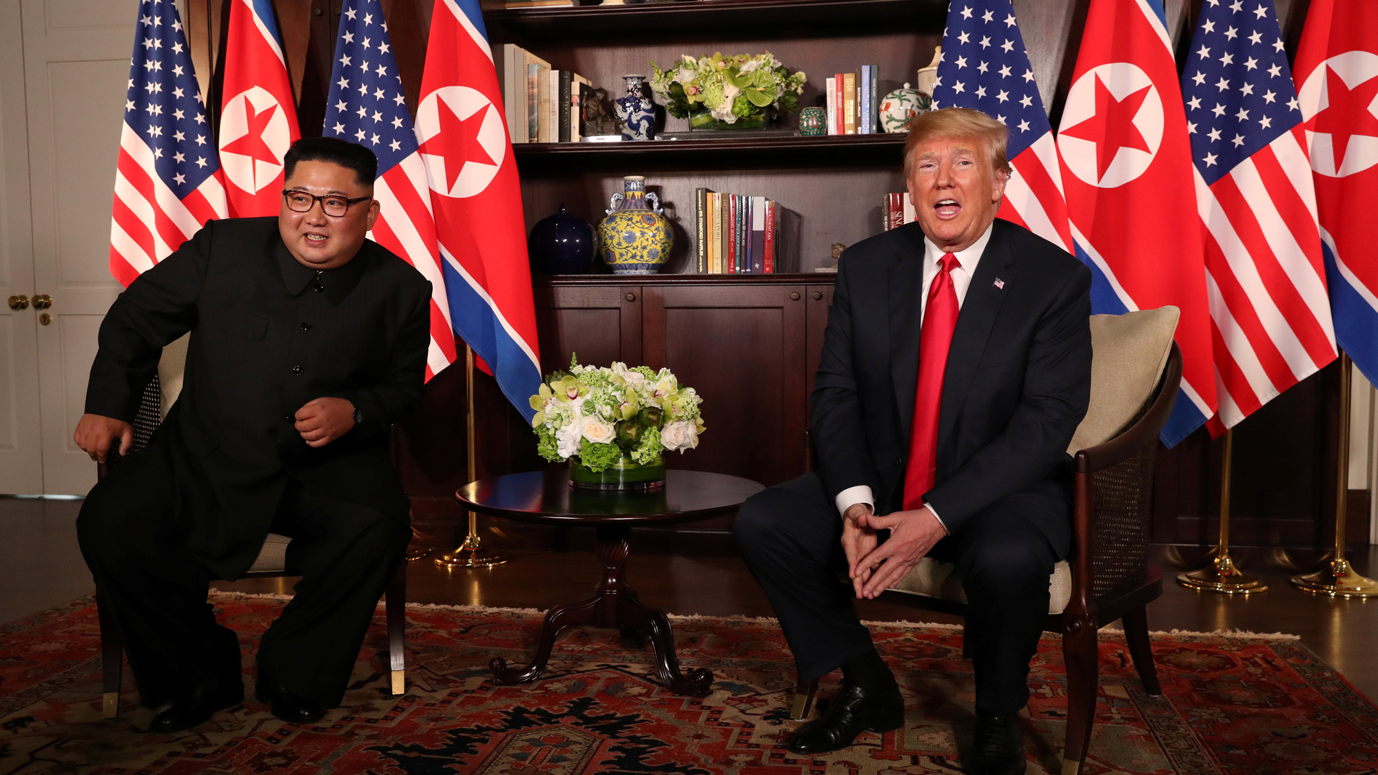 US President Donald Trump sits next to North Korea's leader Kim Jong-un before their bilateral meeting at the Capella Hotel on Sentosa island in Singapore June 12, 2018. US President Donald Trump sits next to North Korea's leader Kim Jong-un with the flags of both countries behind them.