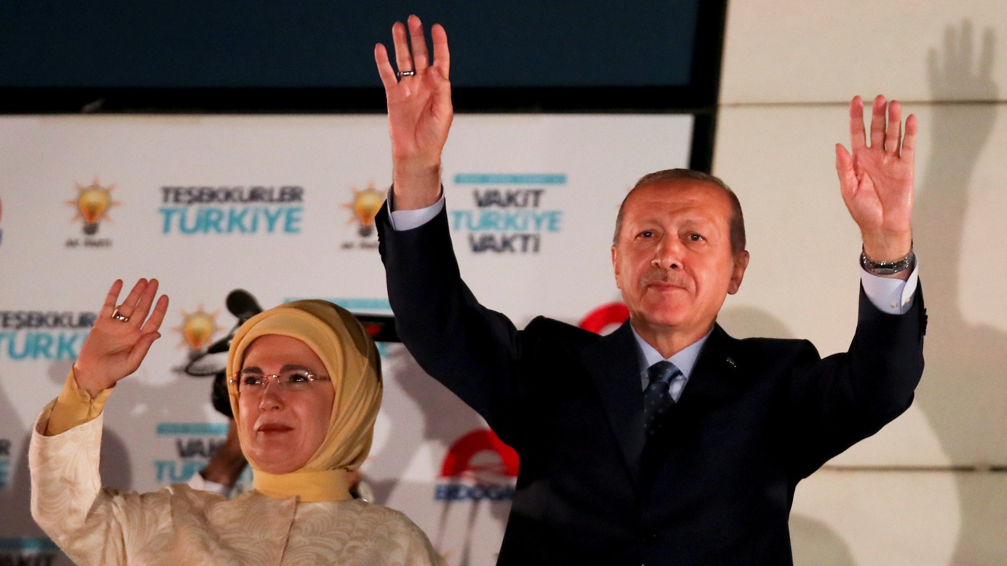 Turkish President Tayyip Erdoğan and his wife Emine Erdogan greet supporters gathered in front of the AKP headquarters in Ankara, Turkey, June 25, 2018. Turkish President Tayyip Erdoğan and his wife Emine Erdogan stand side-by-side with their arms up waving.