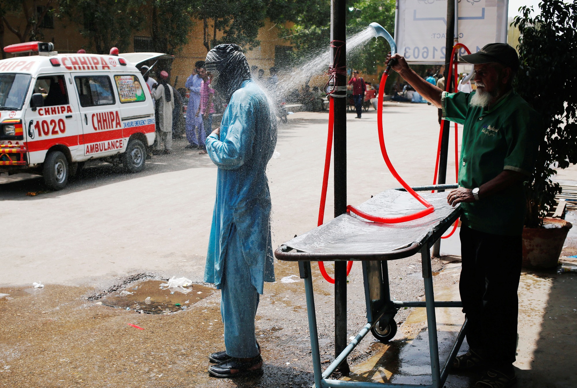 A man cools off with a shower, setup at the premises of the Dr. Ruth K. M. Pfau Civil Hospital, during a heat wave in Karachi, Pakistan. A man cools off with a shower, setup at the premises of the Dr. Ruth K. M. Pfau Civil Hospital, during a heat wave in Karachi, Pakistan.