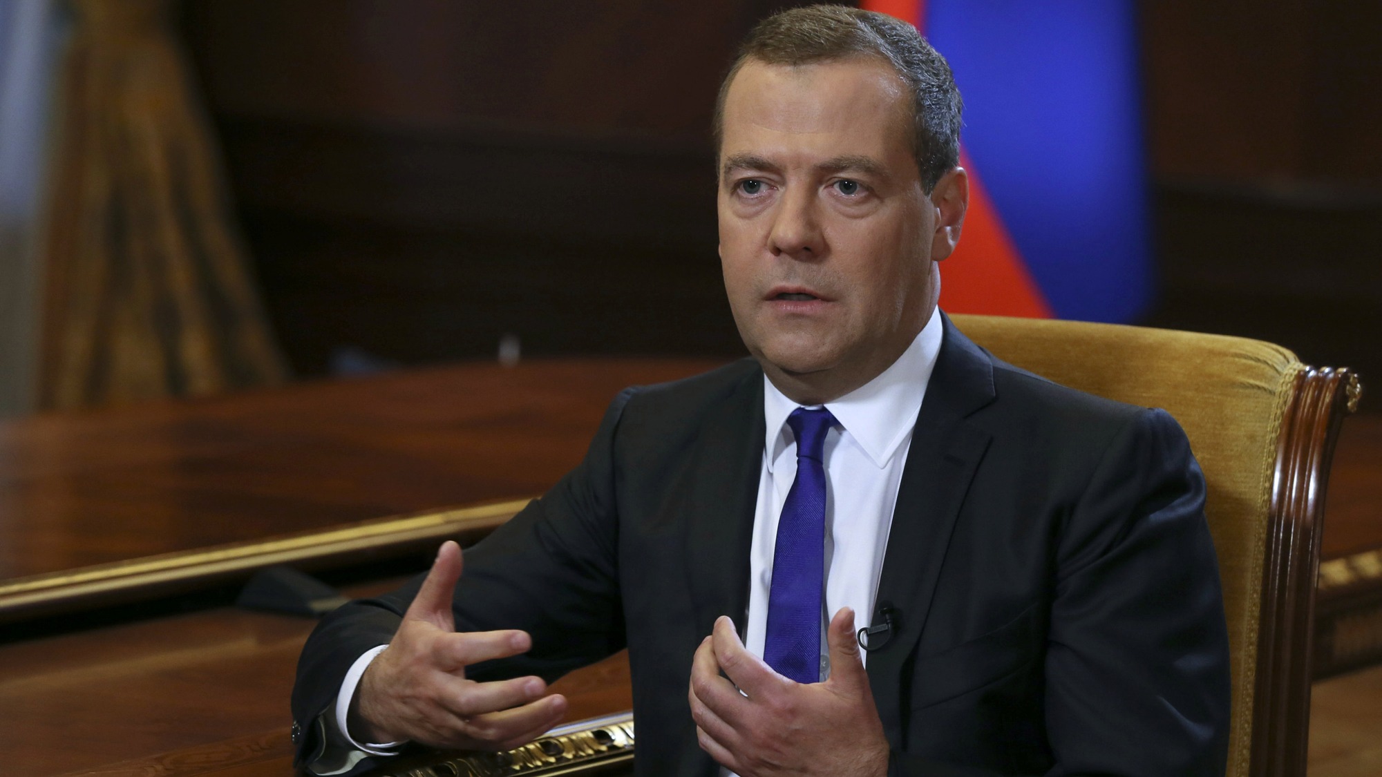 Russian Prime Minister Dmitry Medvedev speaks during an interview outside Moscow. Russian Prime Minister Dmitry Medvedev is shown sitting in a chair with yellow fabric, speaking during an interview outside Moscow.