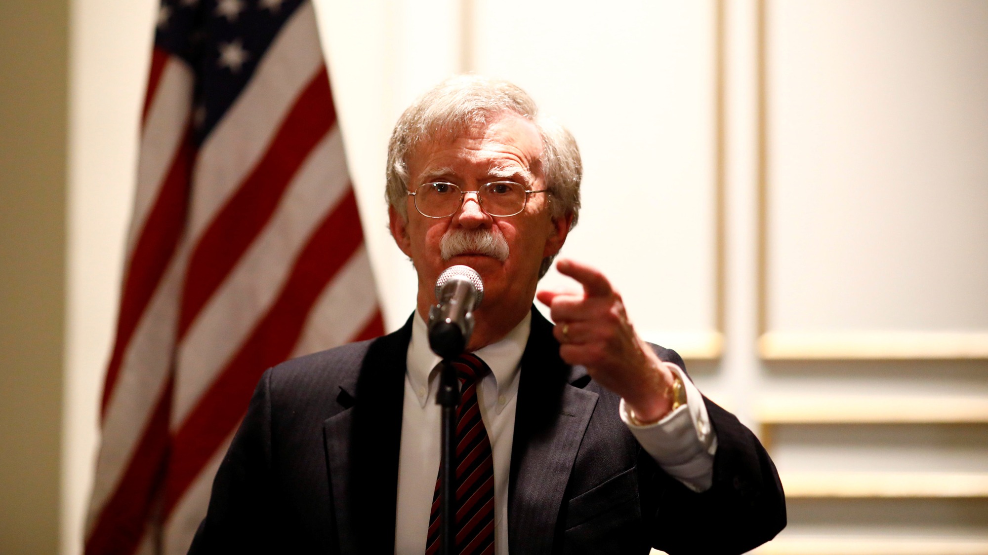 National Security Adviser John Bolton speaks at a forum in Washington, DC, 2018. National Security Adviser John Bolton is shown at a microphone with the US flag behind him, speaking at a forum in Washington, DC, 2018.