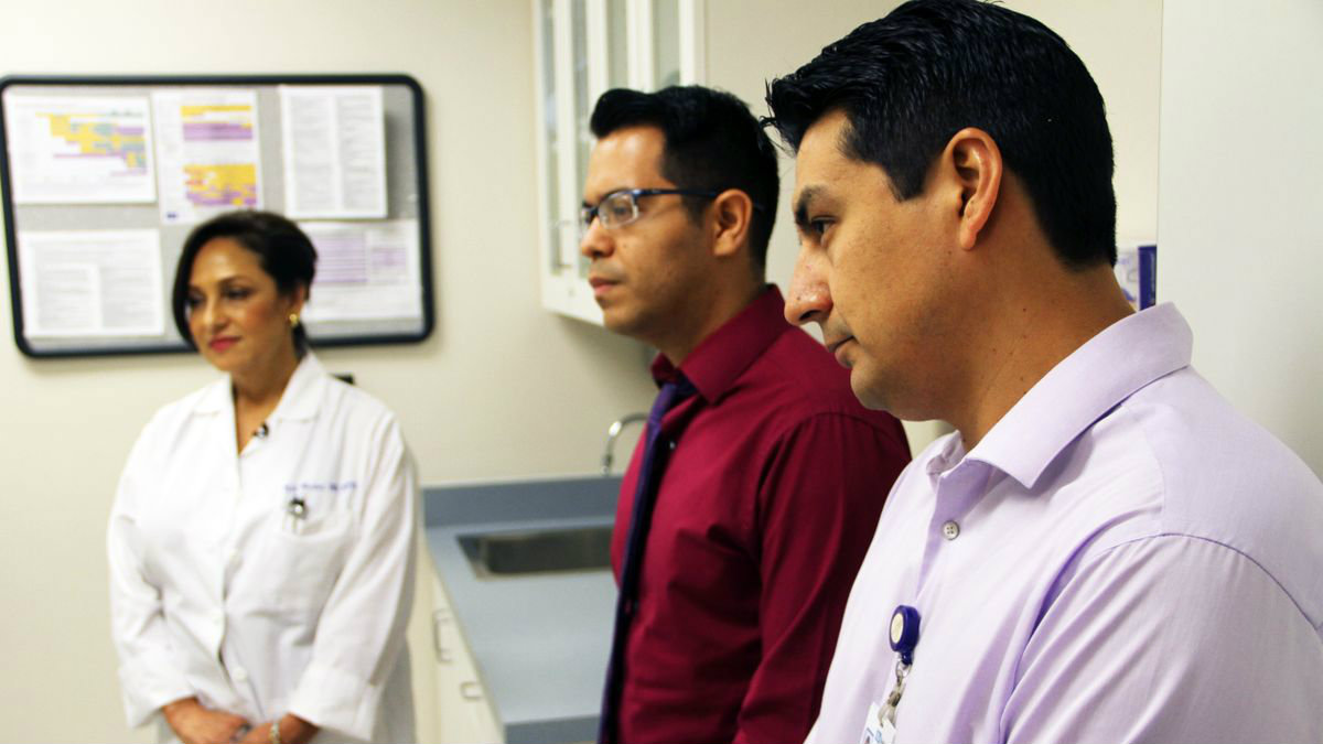 Two male and one female internationally trained doctors are listening to a presentation.