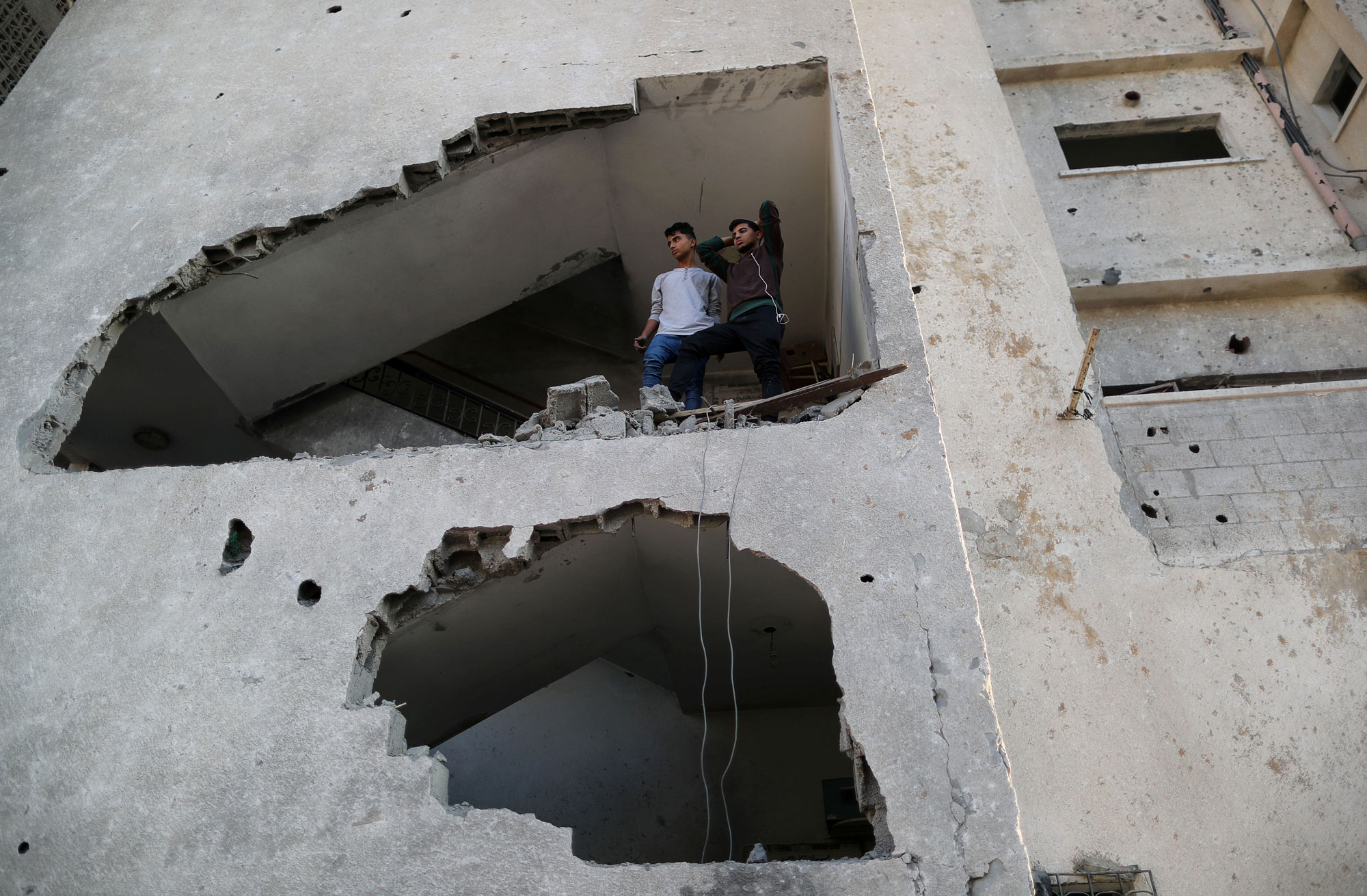 Palestinians look out of their house that was damaged in an Israeli air strike, in Gaza City, Nov. 13, 2018. Palestinians look out of their house through a large hole in the wall created from an Israeli air strike.