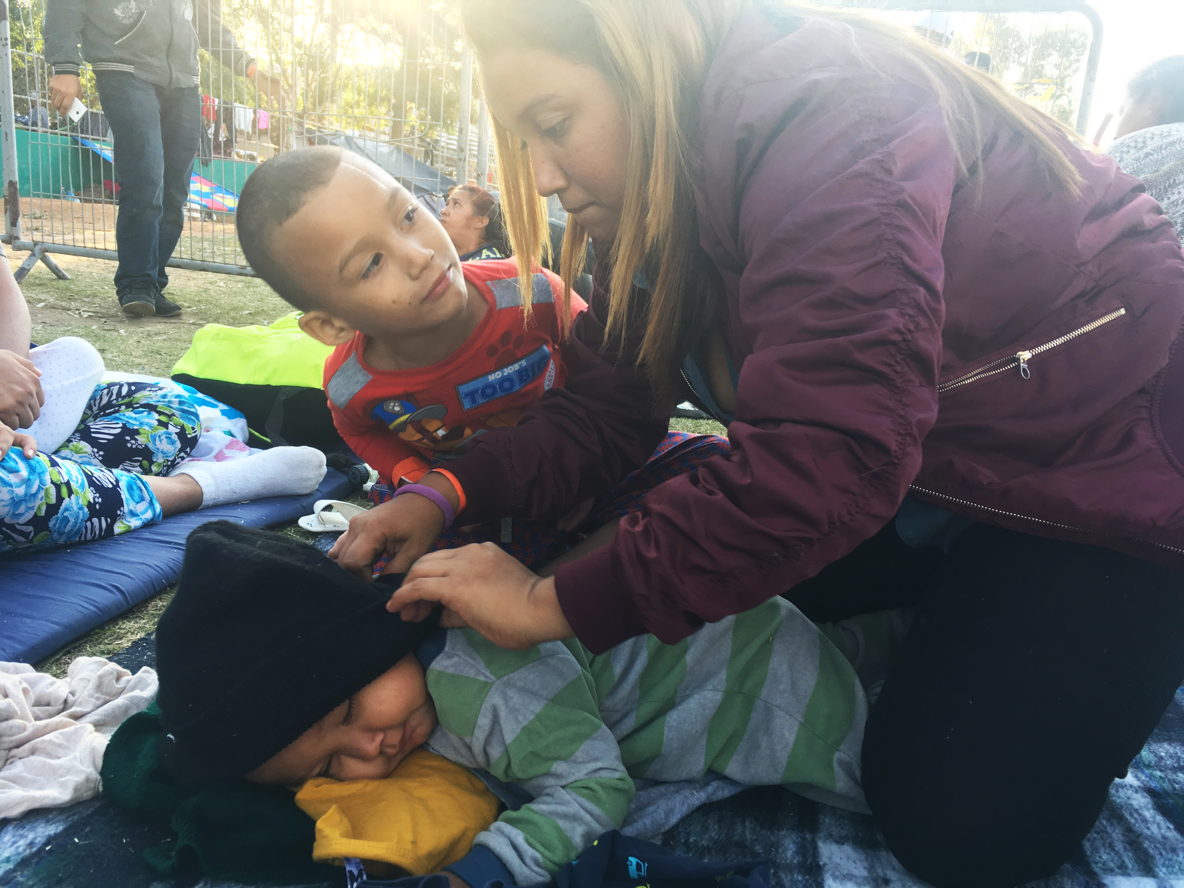 A woman covering her sleeping toddler with a coat