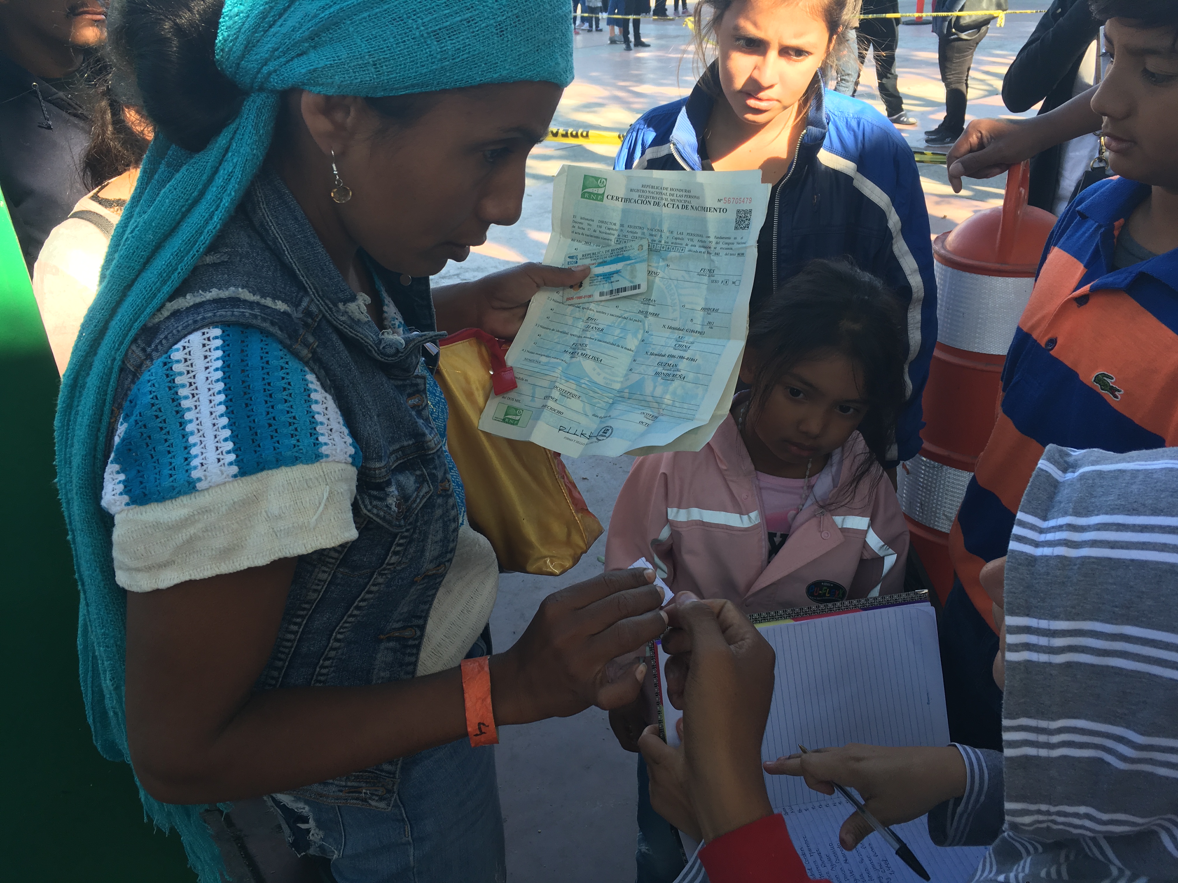 A mother and her kids registering their names in the notebook at the port of entry so they can get on the list to apply for asylum in the US.