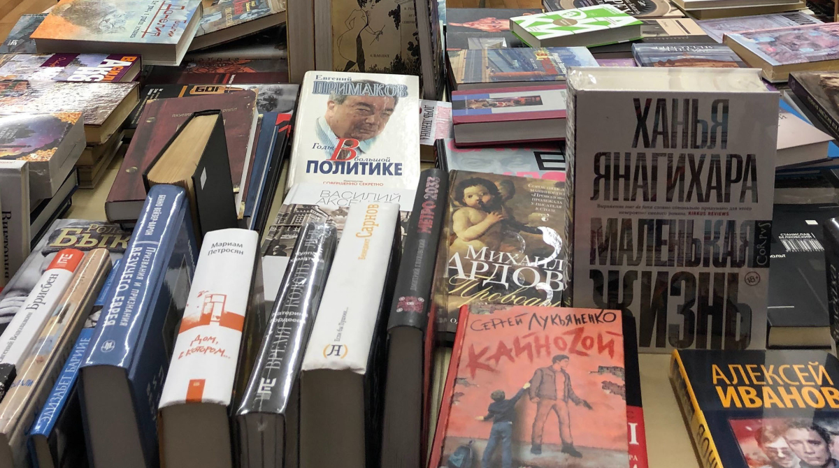 Russian Language books Dozens of books in Russian are on display on a table inside a bookstore.