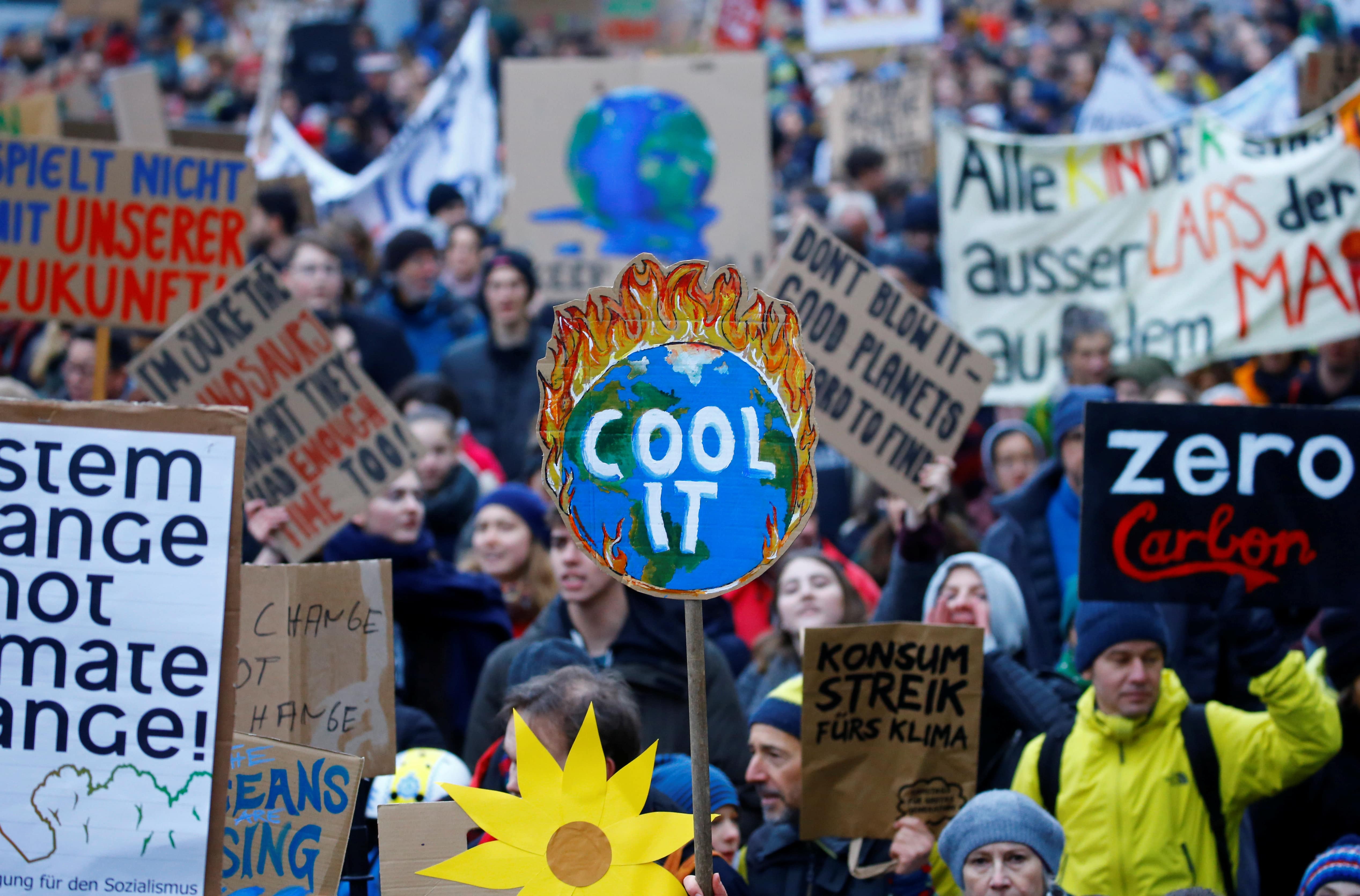 a large crowd of people marching, a sign that read "cool it" is the most prominent