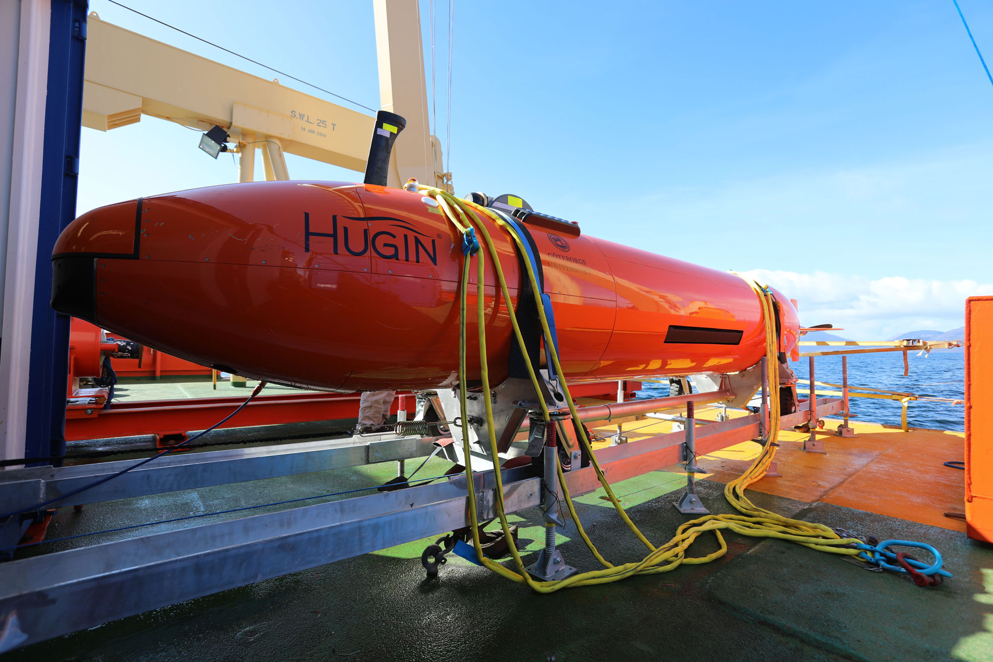 The Hugin on deck. The Hugin, a long orange metal submarine is shown on the deck of the ship.