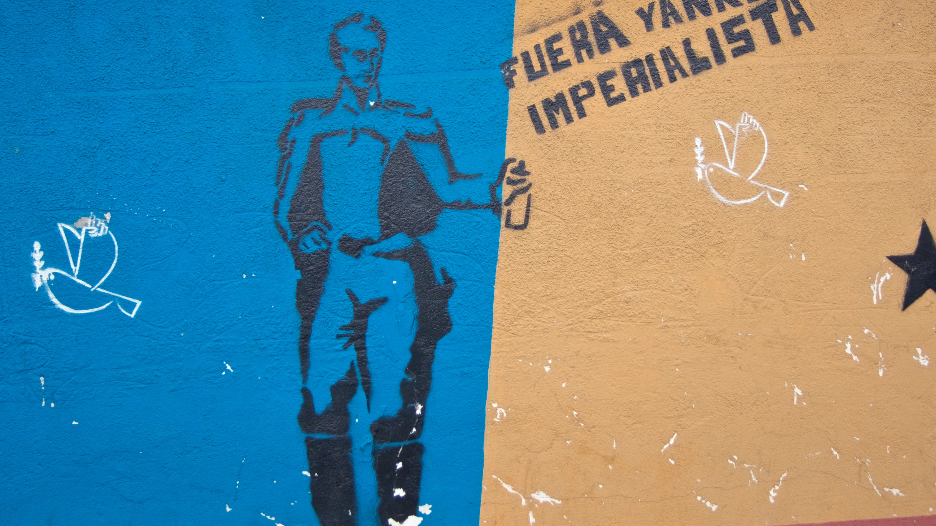 A stencil of Simón Bolívar spray-painting "Out Imperialist Yankee."