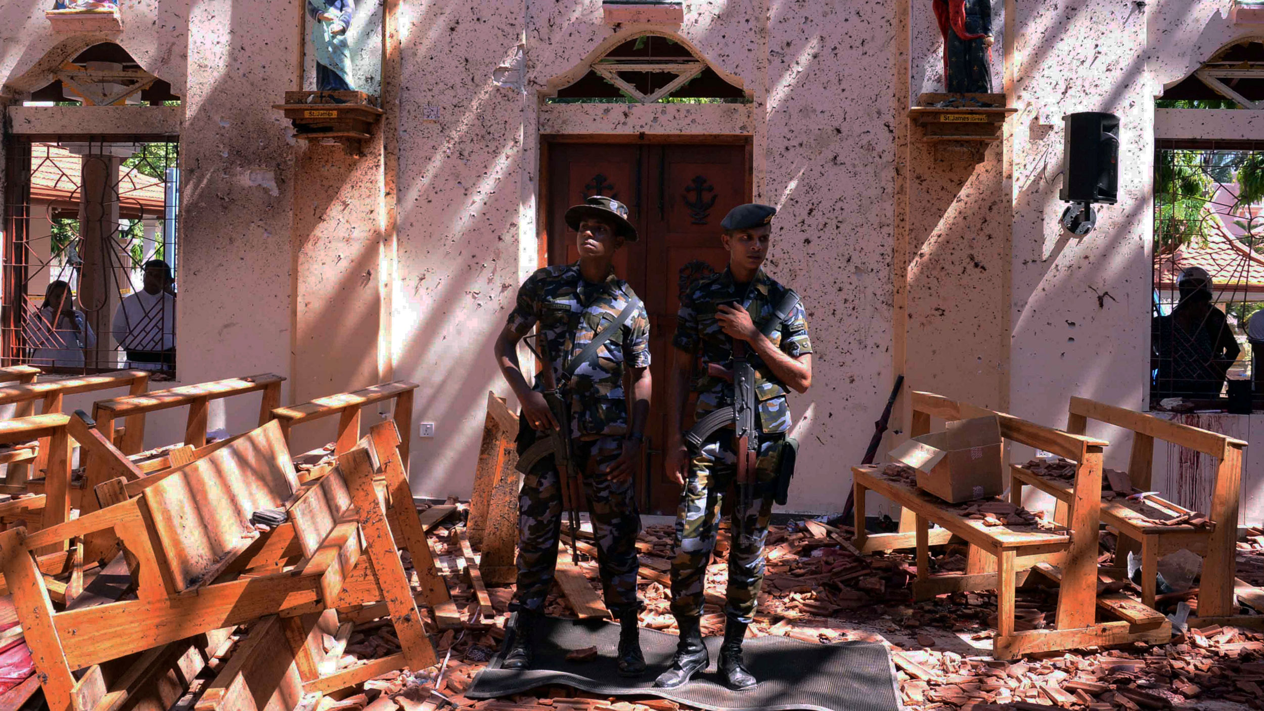 Sri Lankan military stand guard inside a church after an explosion in Negombo, Sri Lanka, April 21, 2019. Two Sri Lankan military are shown standing with weapons over their shoulders in front of a church after an explosion.