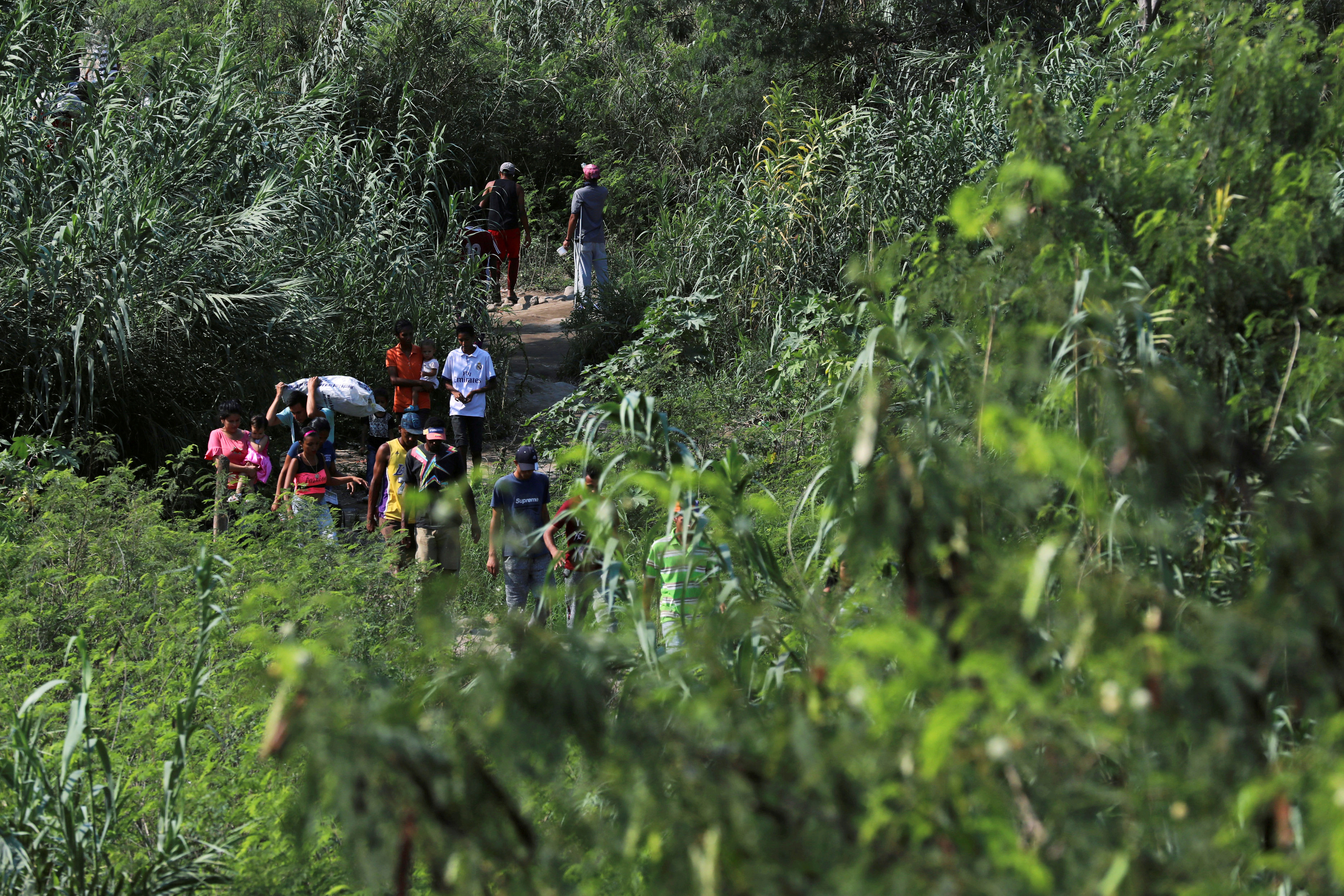 people walk along a path on the venezuela-colombia border