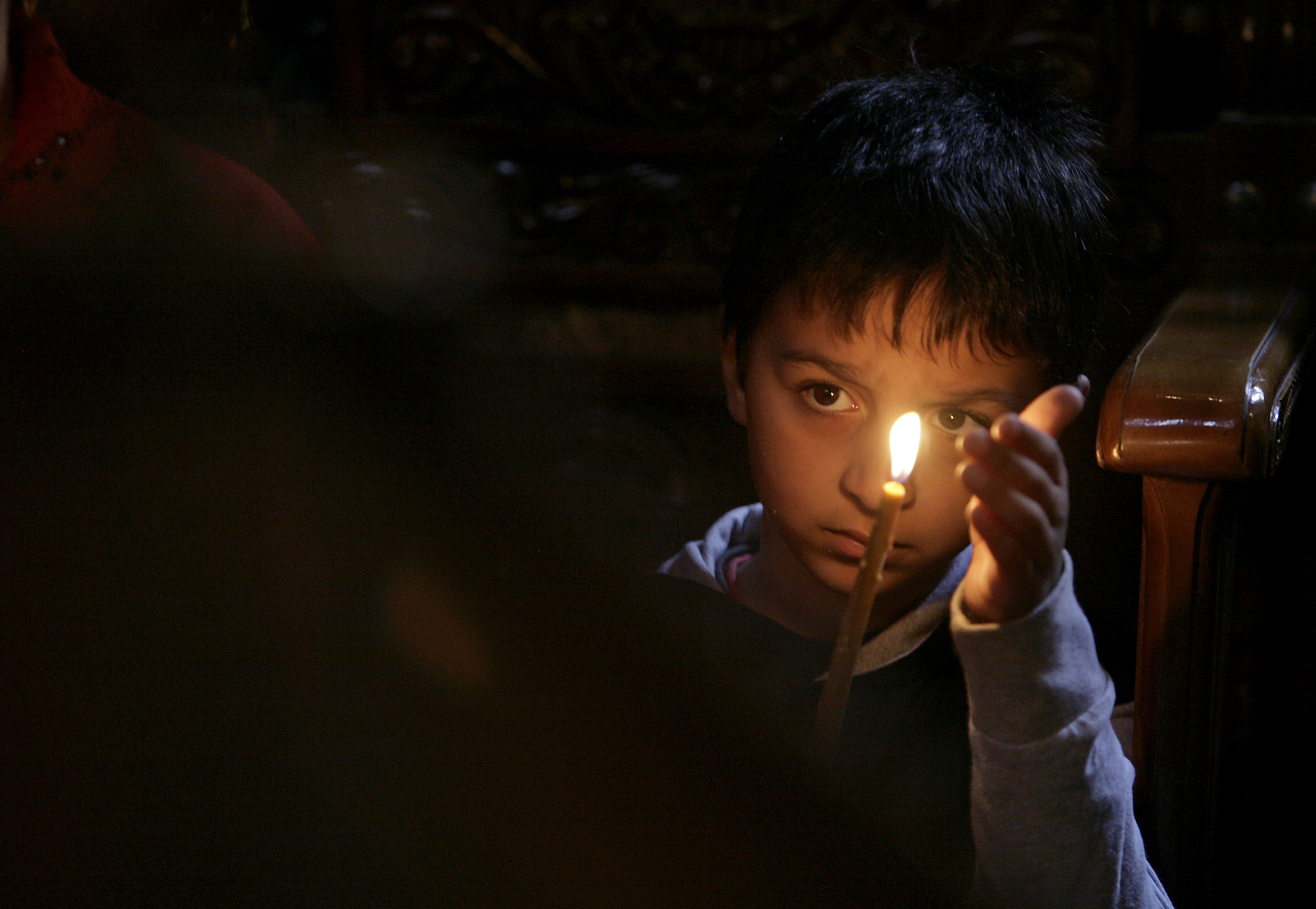 A child from the Roma community holds a candle at a church in Bucharest A child from the Roma community holds a candle at a church in Bucharest