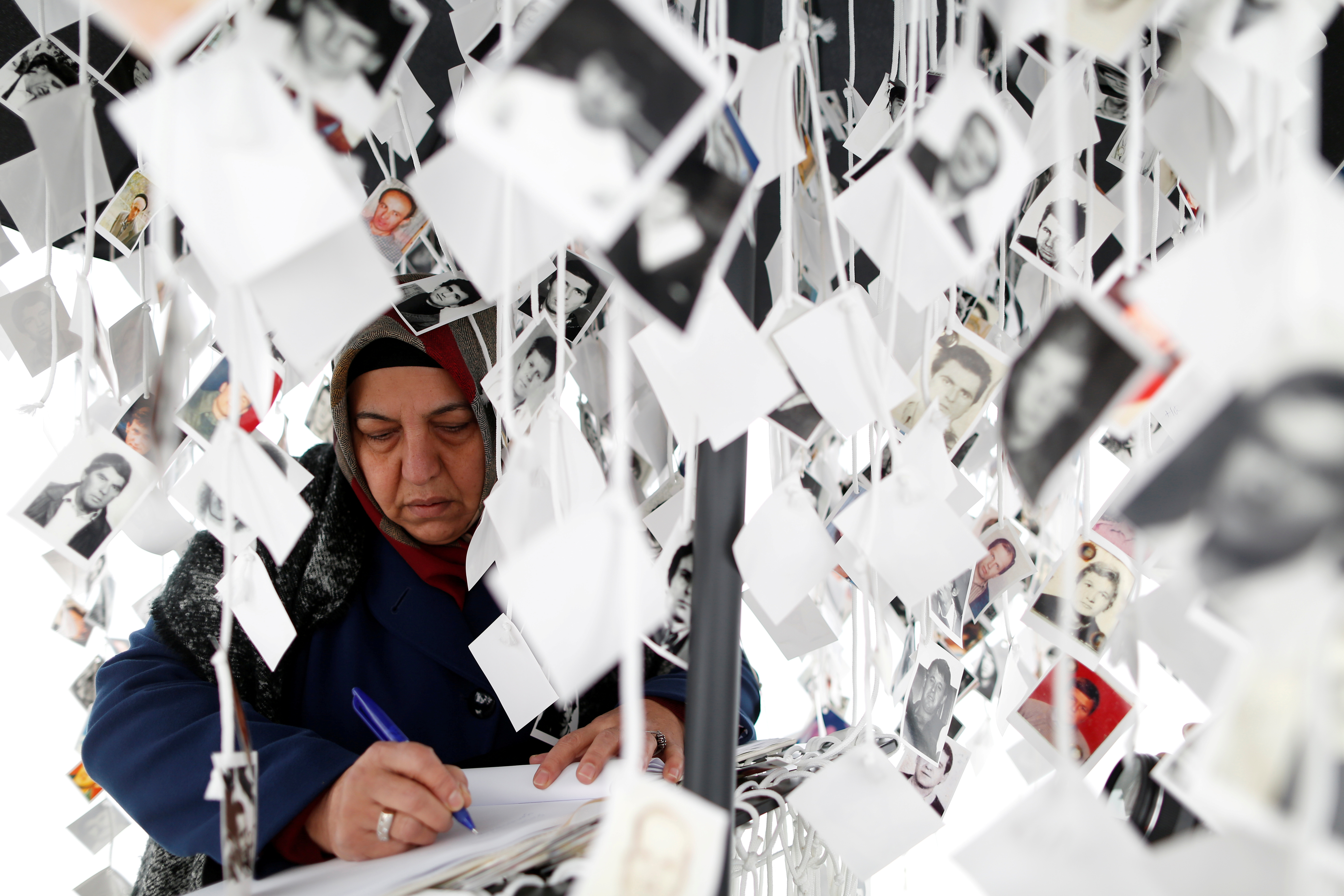 A woman writes in a book inside a traveling monument called 'Prijedor 92' outside the Yugoslav War Crimes Tribunal (ICTY A woman writes in a book inside a traveling monument called 'Prijedor 92' outside the Yugoslav War Crimes Tribunal (ICTY