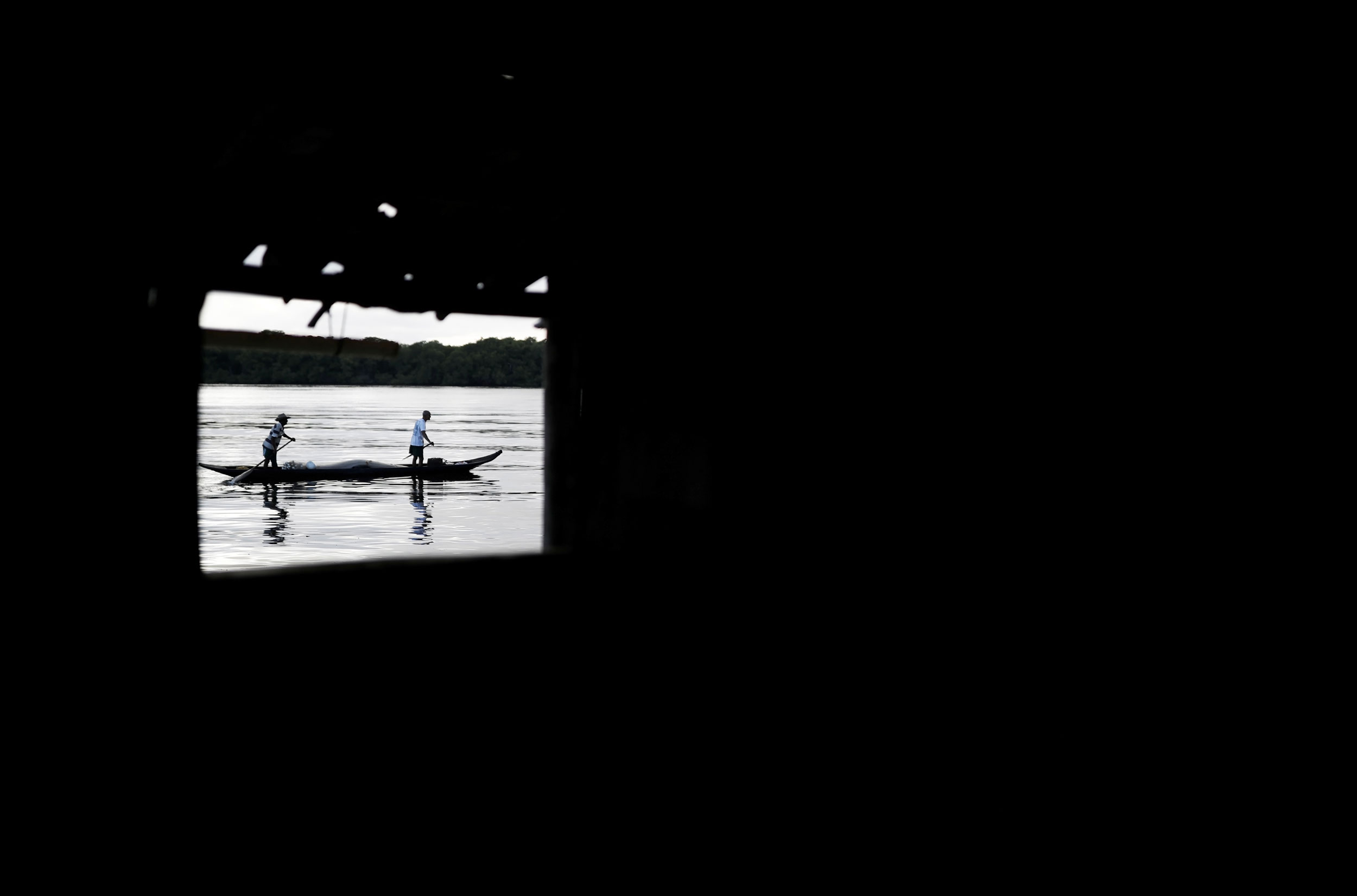 Fishermen are seen through Cruz's window. A dark photograph with a bright window showing people on a boat.