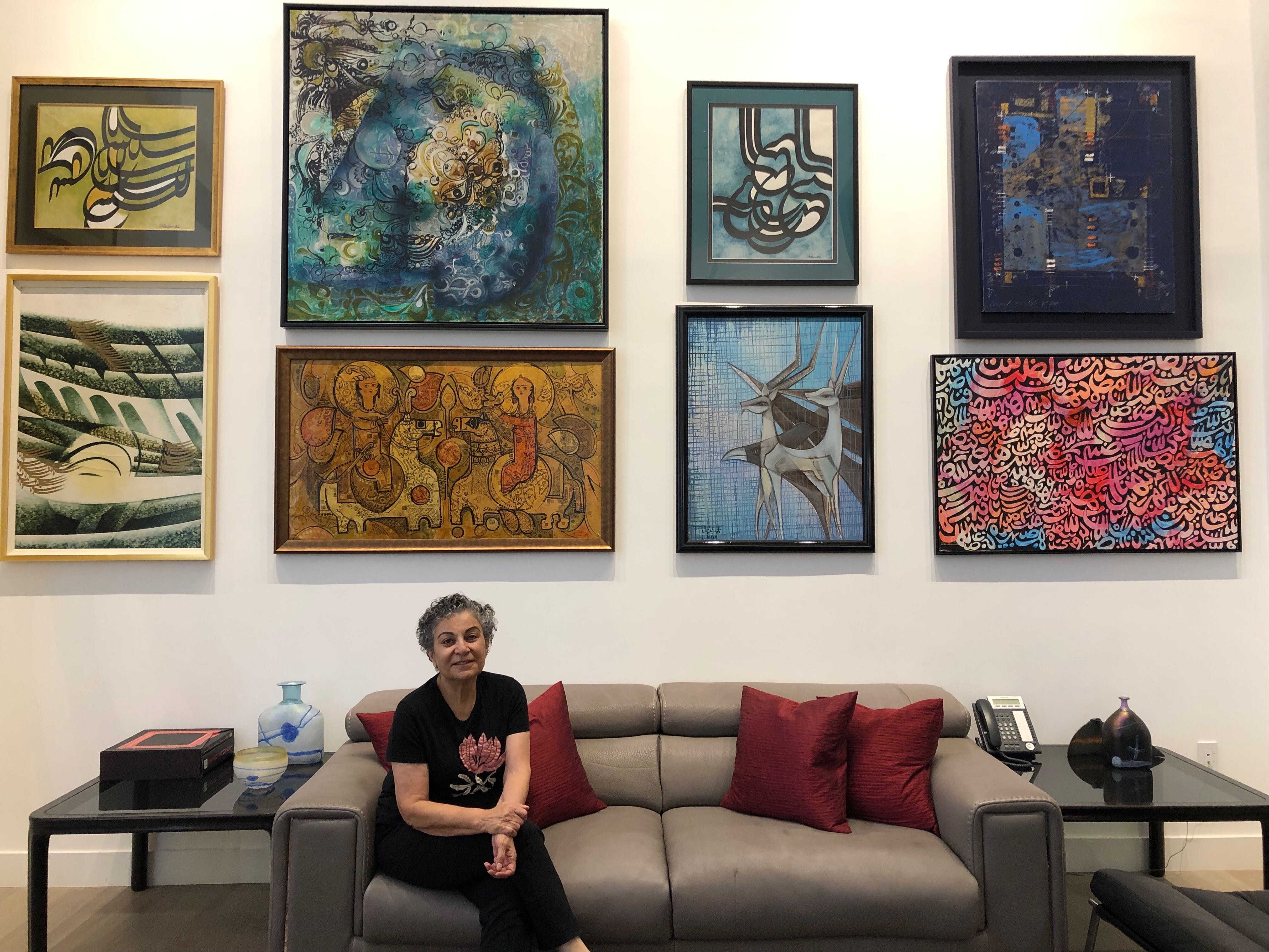Radio host Homa Sarshar at her home in Los Angeles. A woman sits on a couch with several works of art behind her.