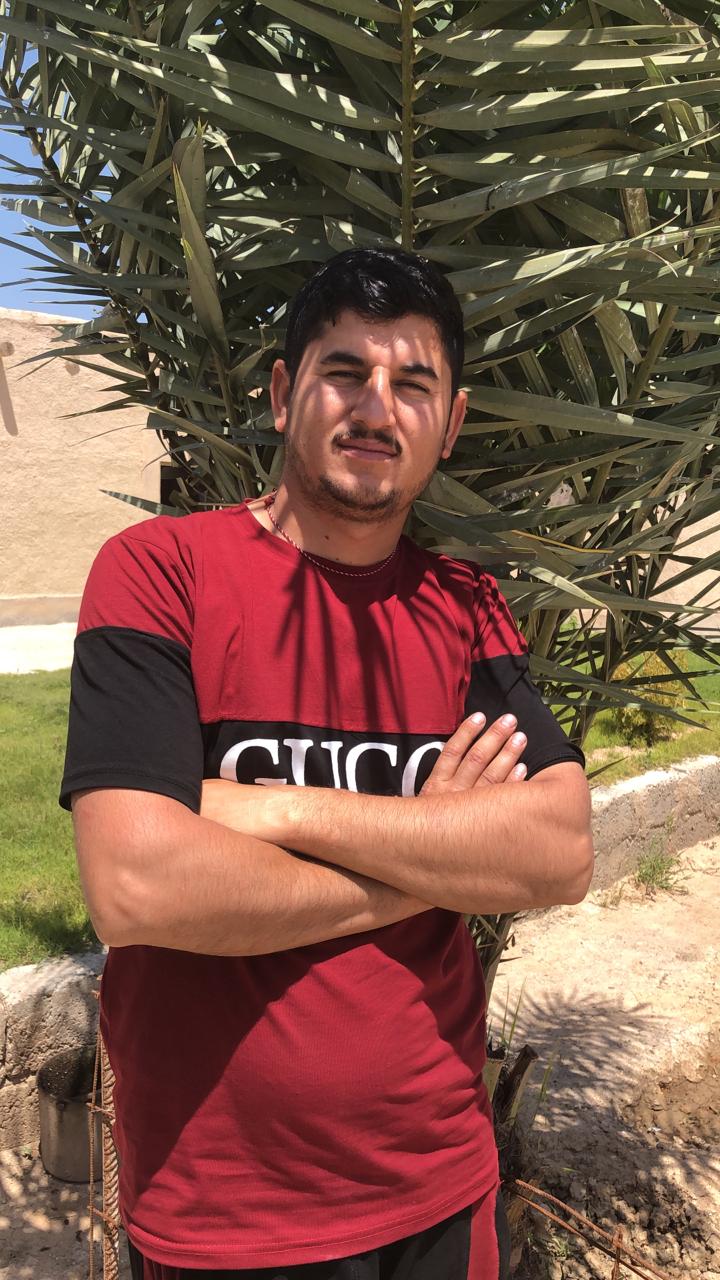 Portrait of man wearing red shirt and poses with arms crossed