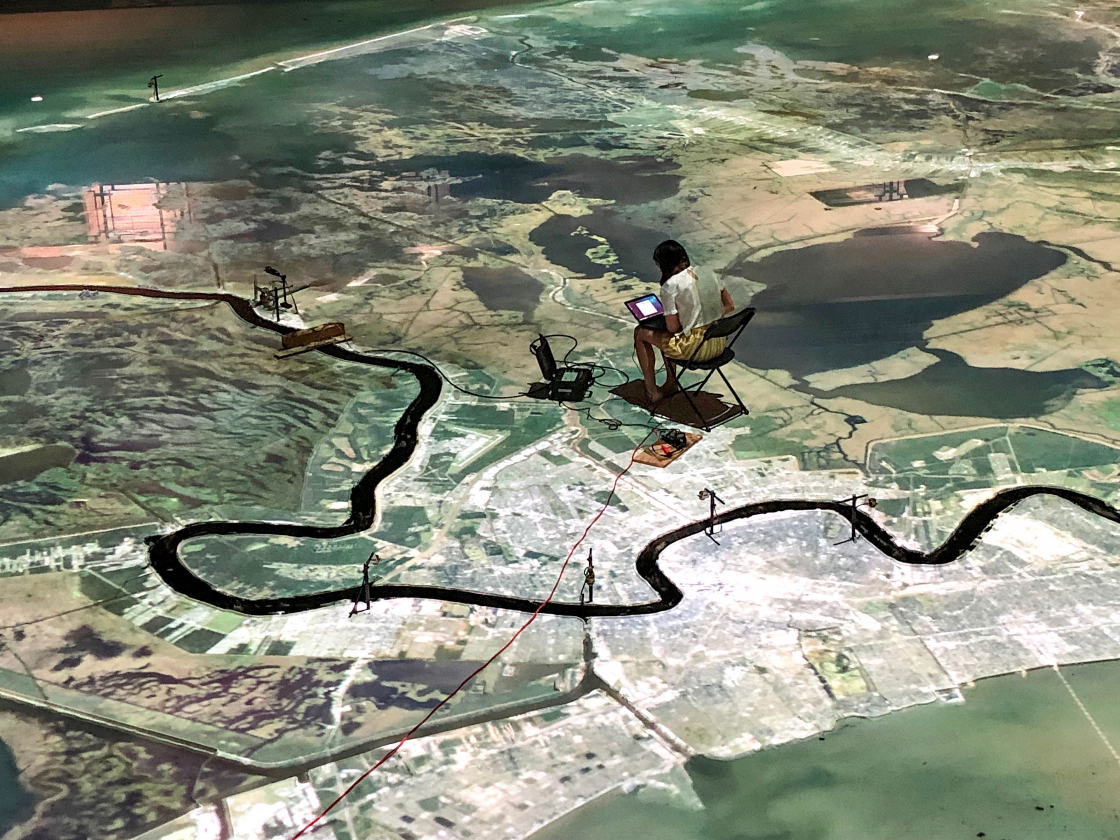 At Louisiana State University in Baton Rouge, engineers are studying the impacts of changes to the lower Mississippi River and coastal Louisiana. A large scale map of the Mississippi River is shown from above with a person sitting in a chair on the map.