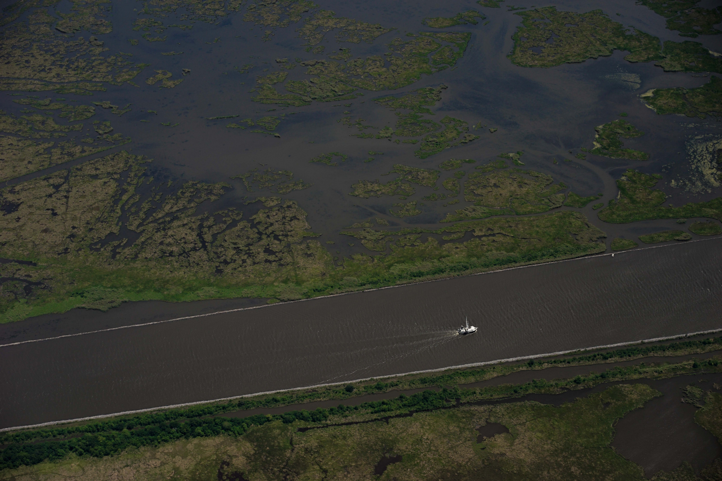 Vast stretches of the Mississippi River no longer resemble a natural river system, but rather a canal straitjacketed by levees and walls. A view of the Mississippi River from an airplane above showing a straightened section of the formerly curvy river.