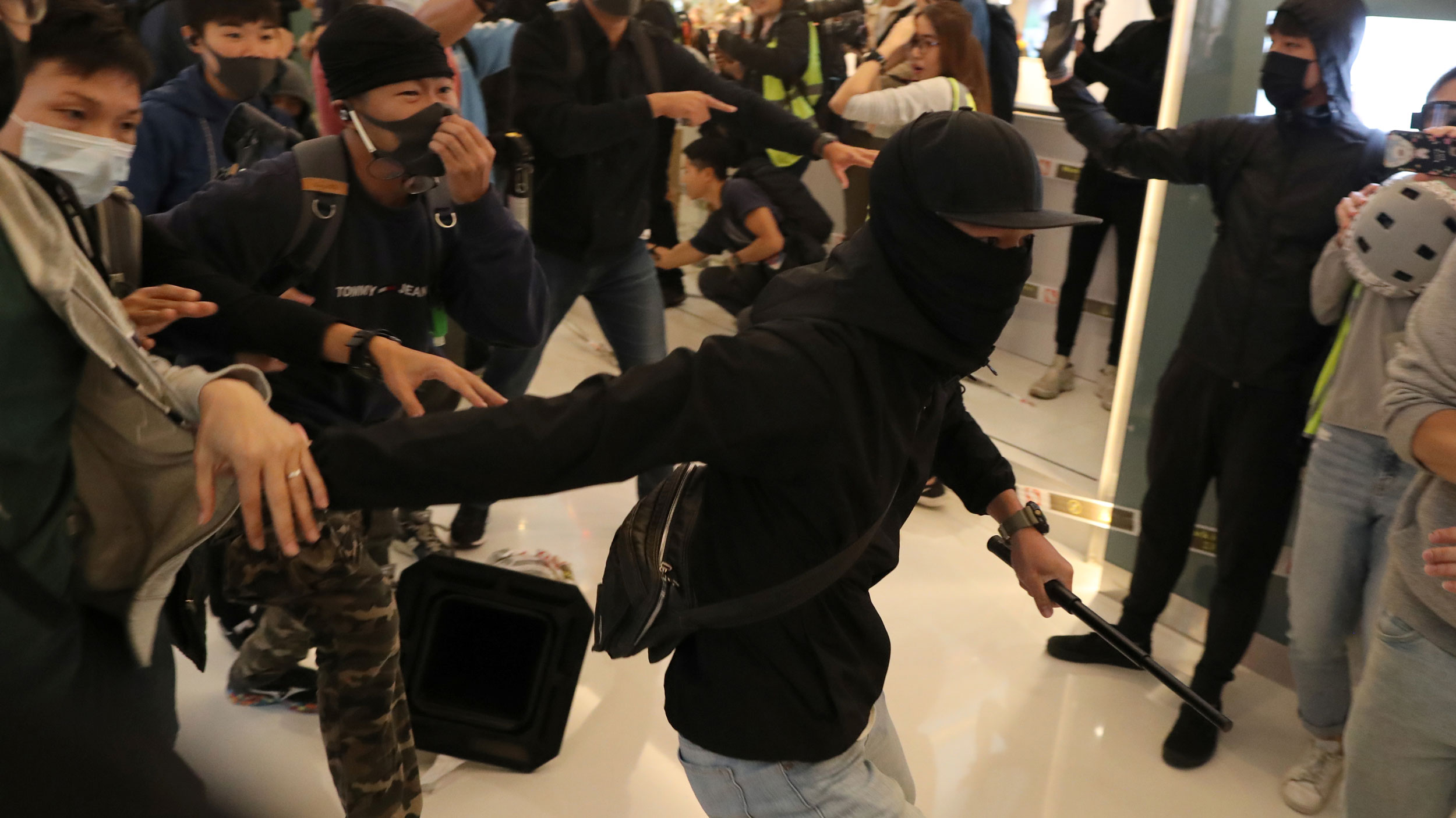 A newspaper stall owner wears a gas mask as riot police stand guard around Mongkok during anti-government protest on Christmas day in Hong Kong, China, on Dec. 25, 2019. A newspaper stall owner wears a gas mask