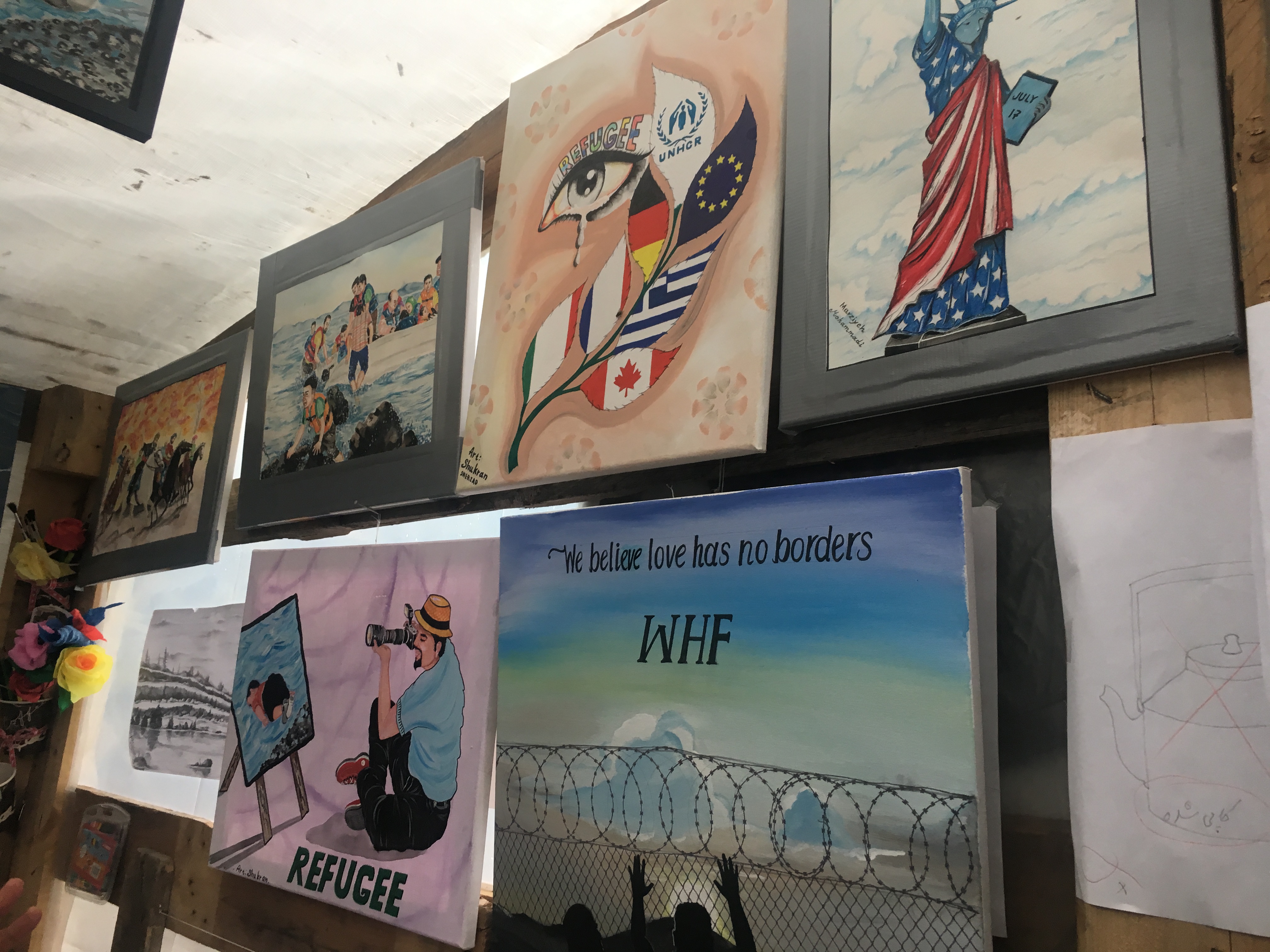 A wall of children's paintings express the daily realities and fears of living as refugees in Moria Camp, Lesbos, Greece. A wall of children's art work