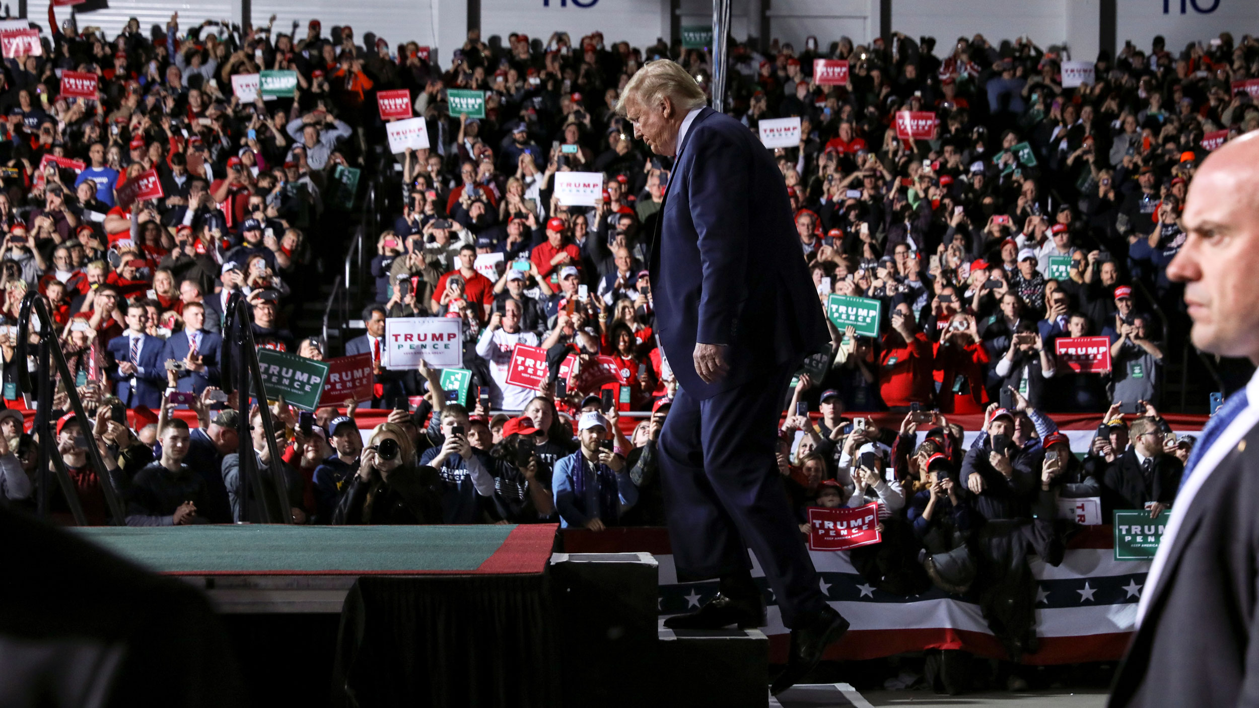 US President Donald Trump walks up the stage to speak to supporters during a campaign rally in Battle Creek, Michigan, Dec. 18, 2019. US President Donald Trump is shown walking up the steps of a stage with an audience in the distance.