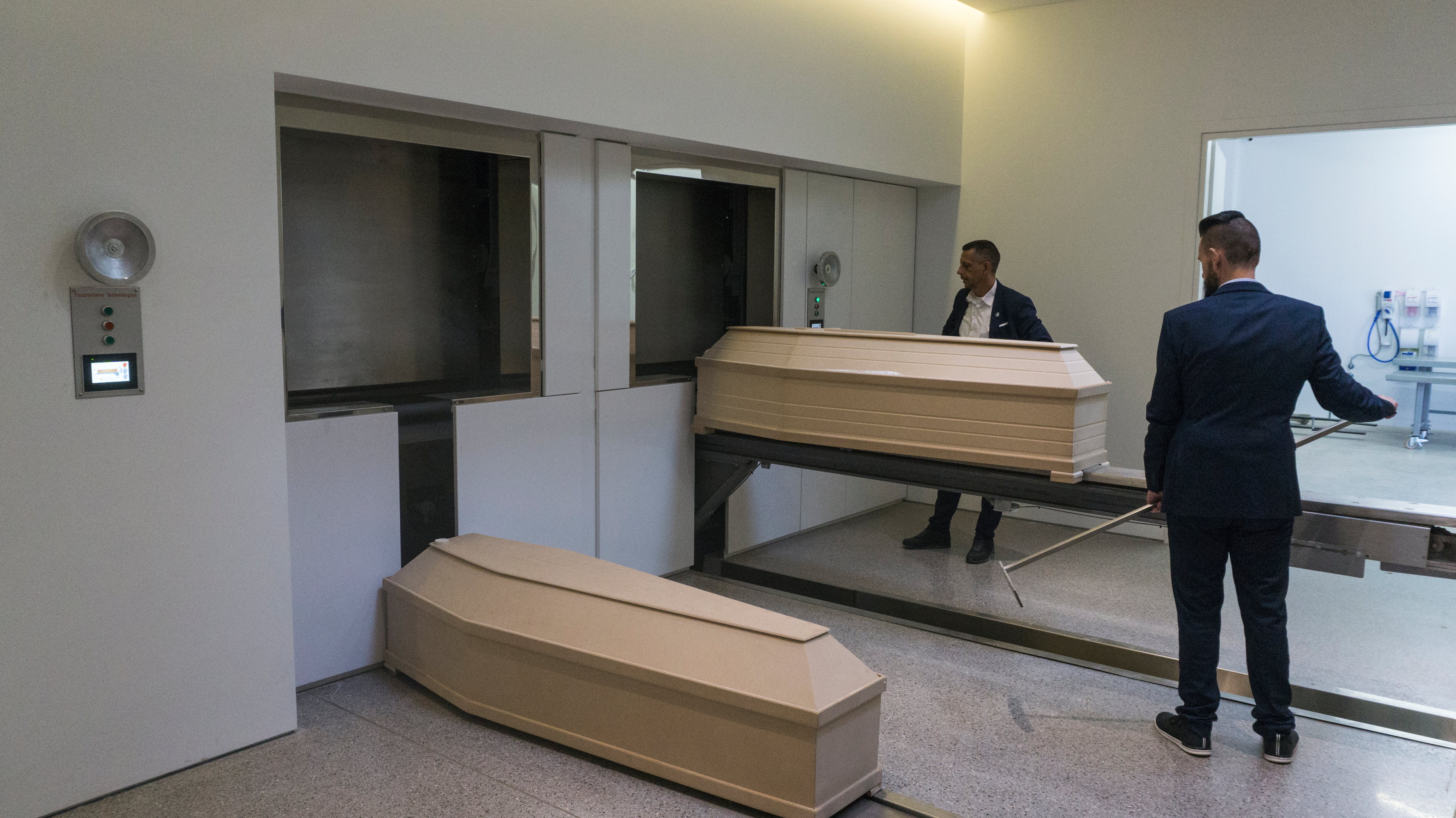 The first and only crematorium in the city of Ritsona, just outside of Athens, has finally opened. Owned privately, a public crematorium has not yet been built although it has been legal since 2006. Two men in suits place beige-colored coffins in incinerators