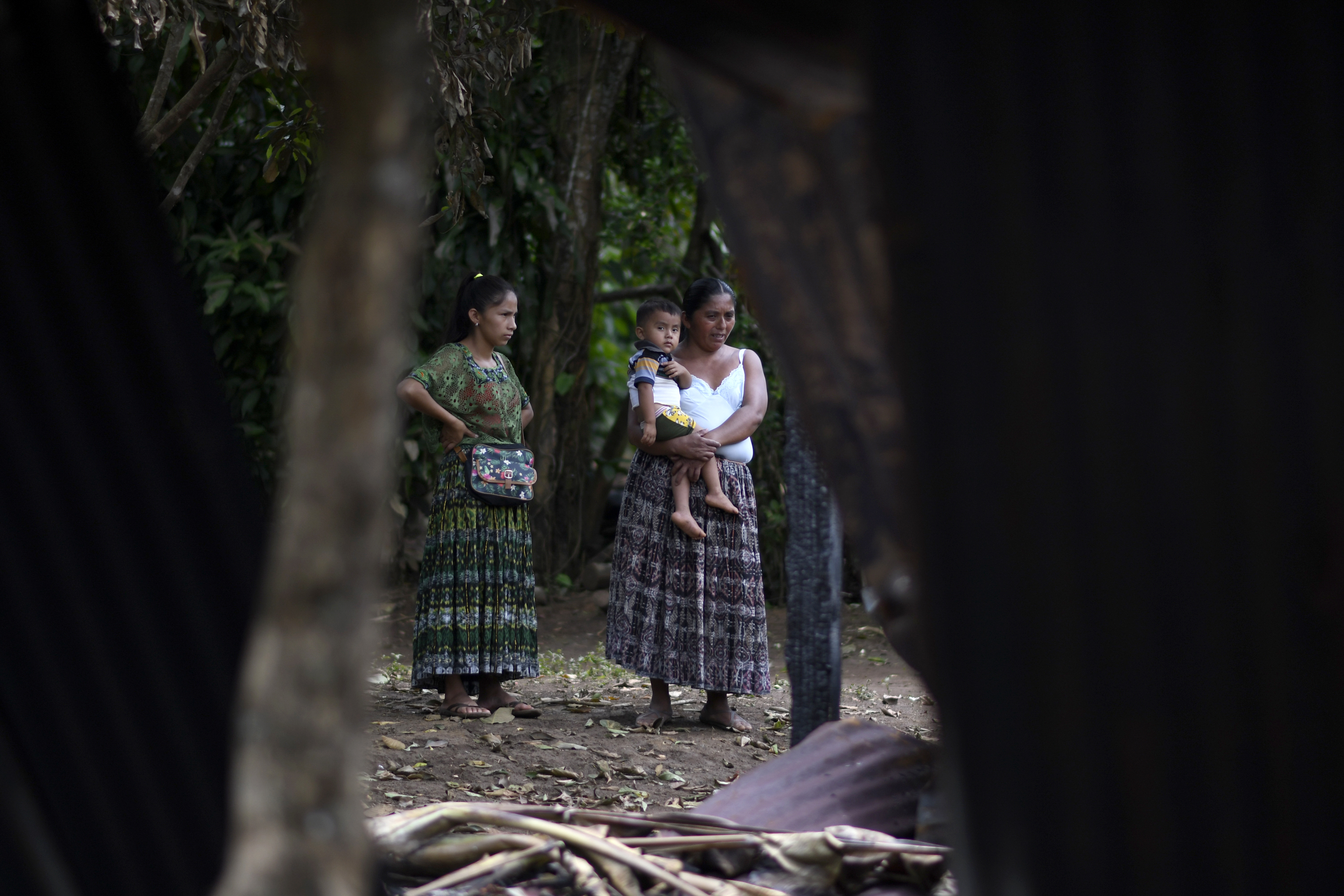 A standing woman holds a baby on her hip next to another woman.