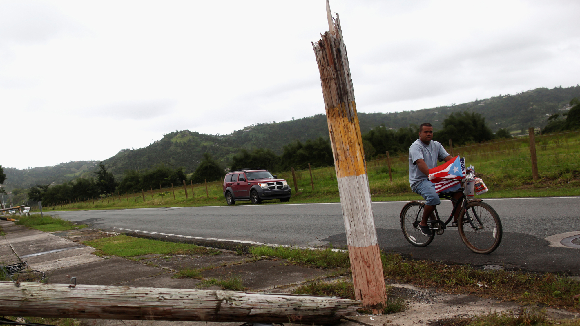 A man rides a bicycle past a collapsed utility pole after Hurricane Maria hit the island in September 2017. A man rides a bicycle past a collapsed utility pole after Hurricane Maria hit the island in September 2017.
