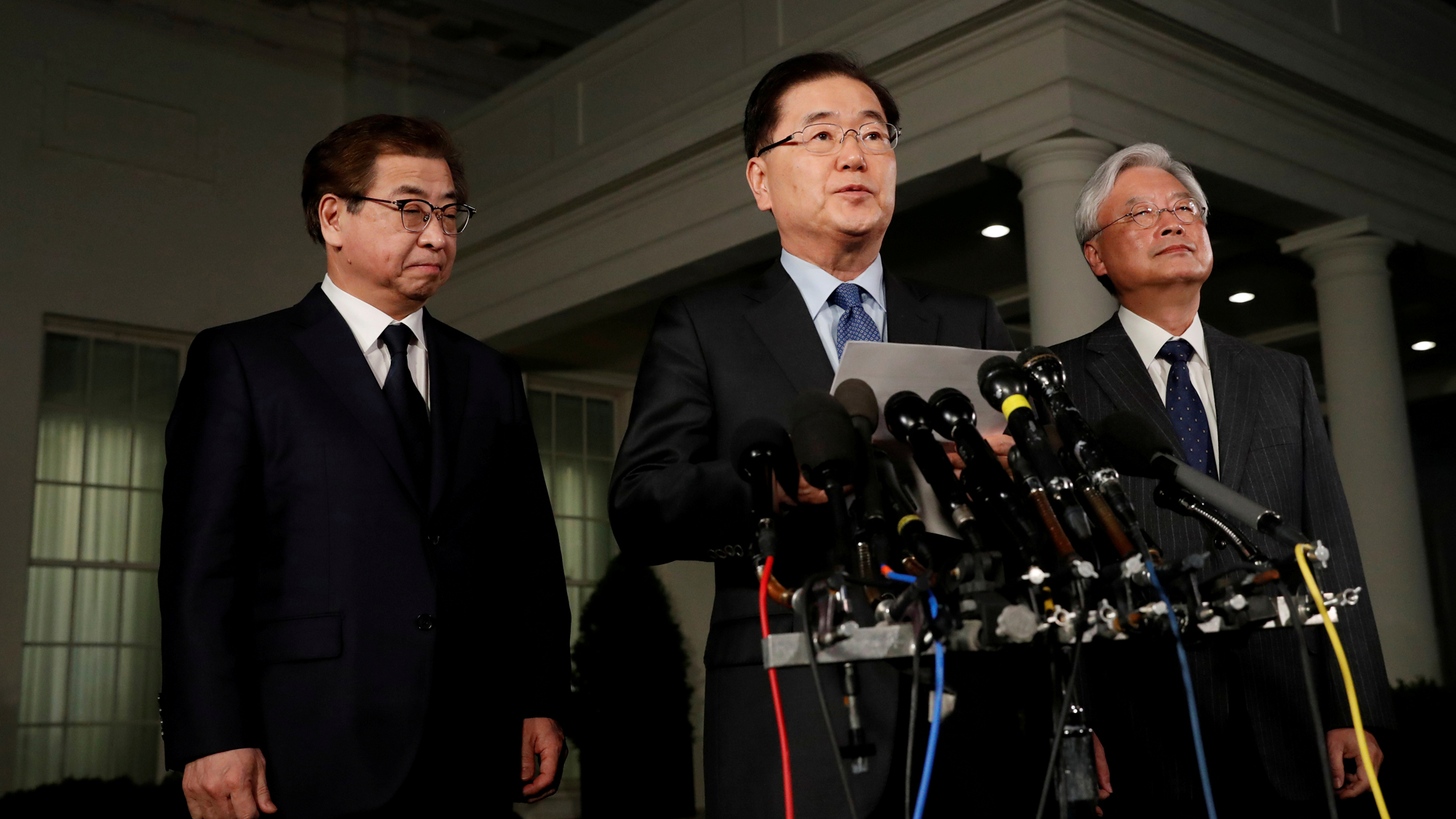 South Korea's National Security Office head Chung Eui-yong, Cho Yoon-je, the South Korean Ambassador to the US and National Intelligence Service chief Suh Hoon (L), make an announcement about North Korea and the Trump administration outside of the West Wi South Korea's National Security Office head Chung Eui-yong stands at a podium making an announcement.