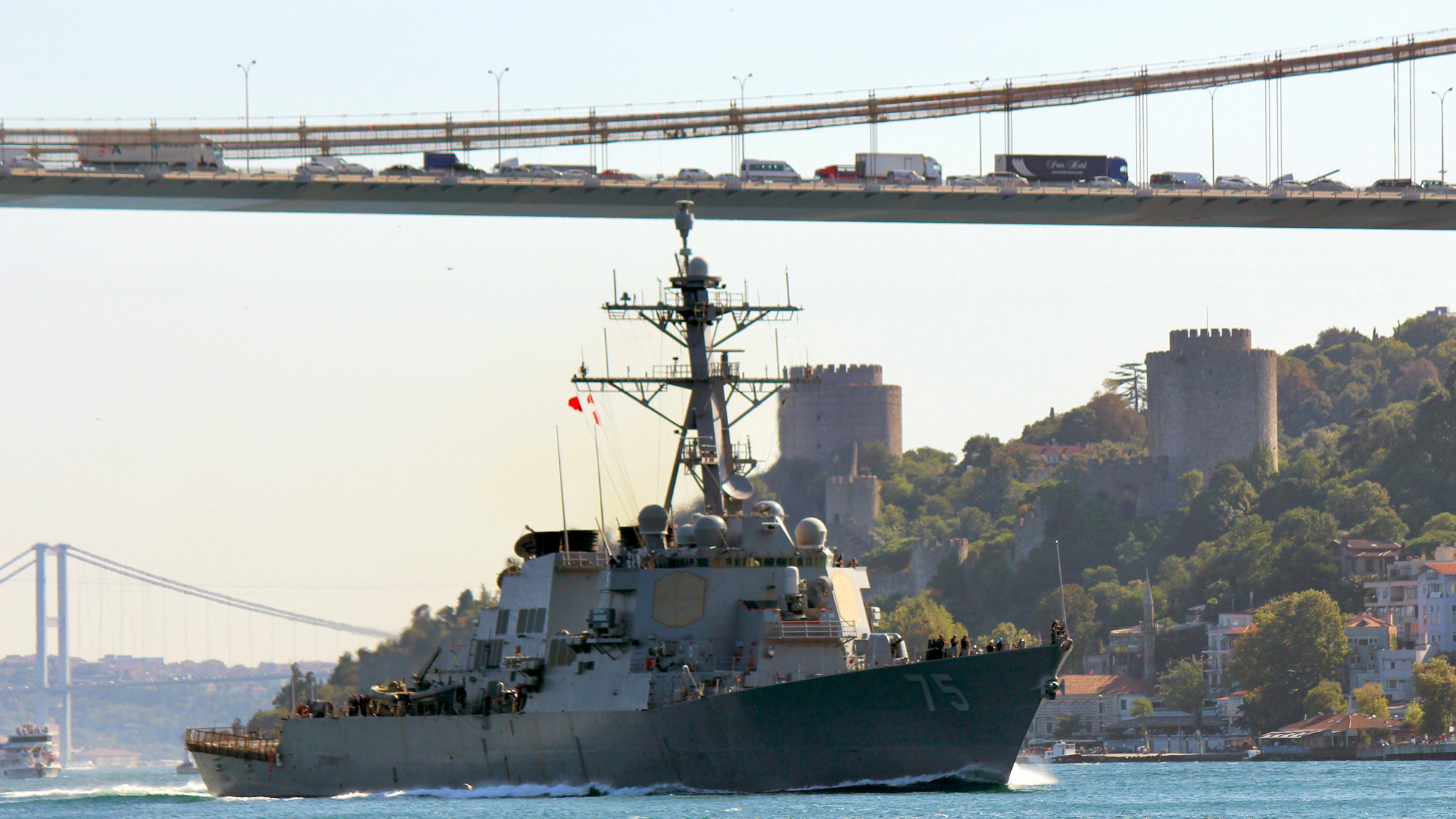 The US Navy Arleigh Burke-class guided-missile destroyer USS Donald Cook sails in the Bosphorus strait in Istanbul, Turkey. USS Donald Cook sails in the Bosphorus strait in Istanbul with a long cable bridge in the background.