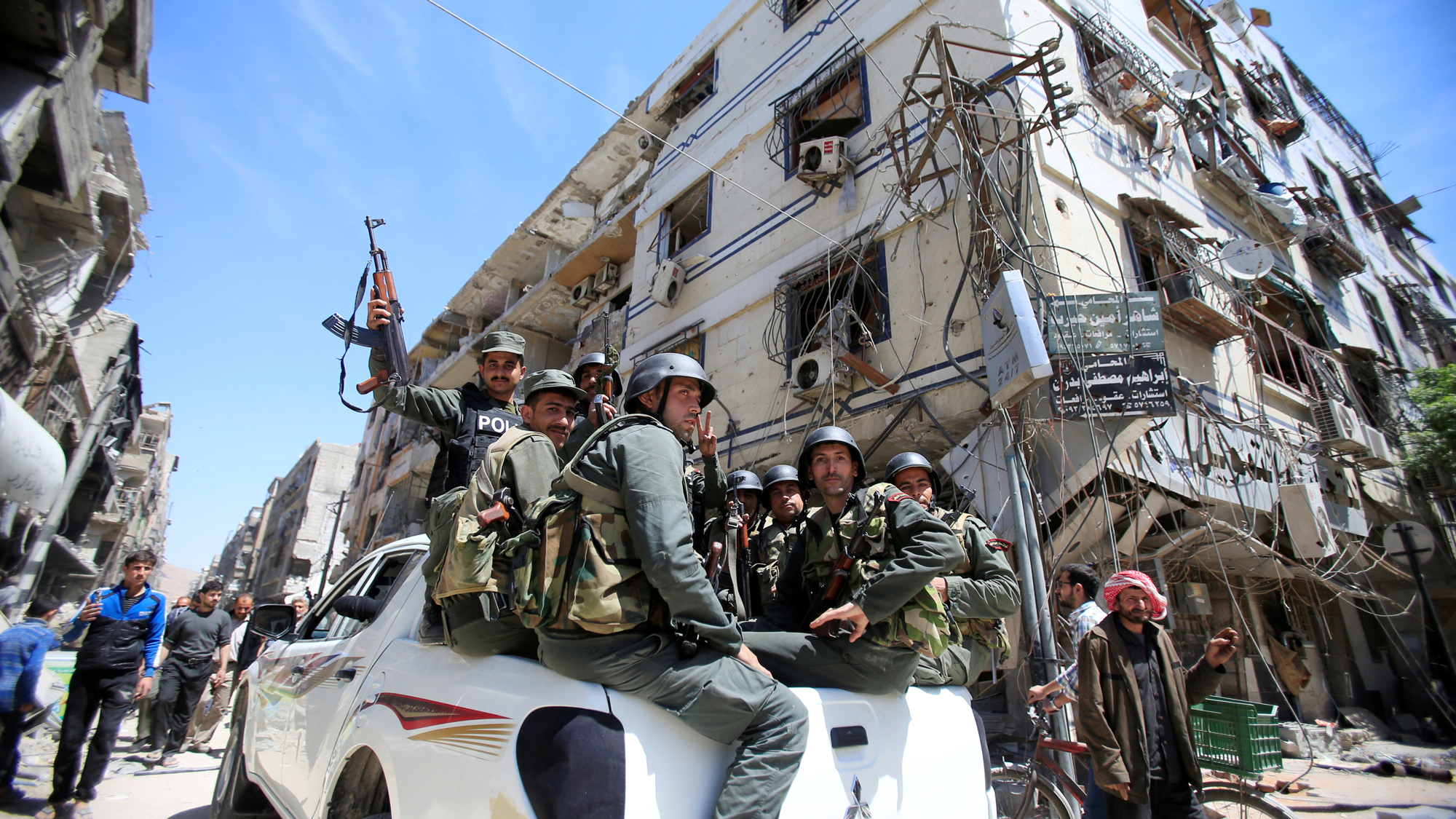 Members of the Syrian police hold their weapons as they sit on a back of a truck at the city of Doma, Damascus, Syria April 16, 2018. Syrian police hold weapons while they ride in the bed of a pickup truck in Doma.