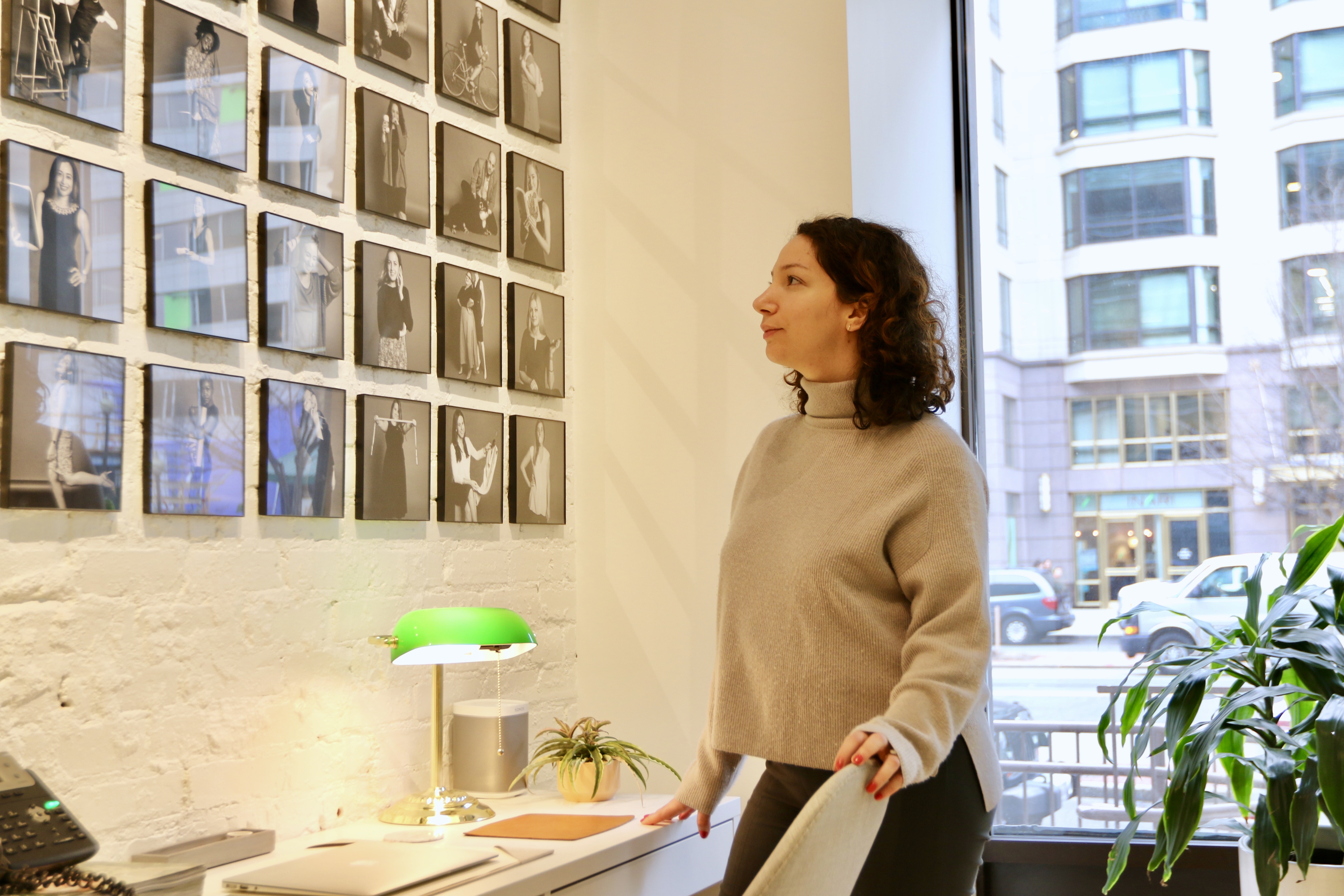 A woman looks at photographs on the wall.