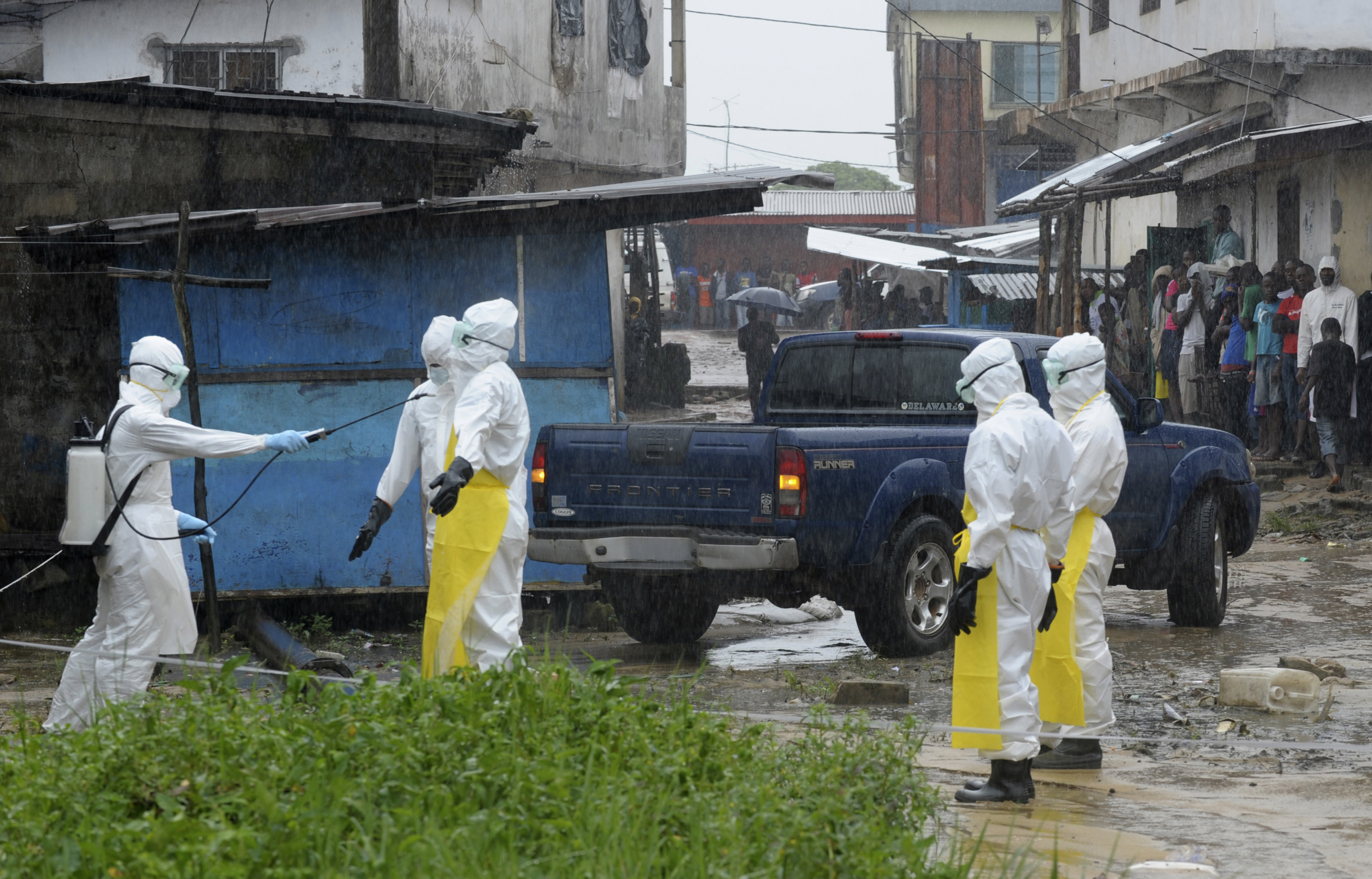Health workers wearing protective clothing disinfect themselves after an abandoned dead body presenting with Ebola symptoms was found at Duwala market in Monrovia, Liberia, on August 17, 2014. Health workers wearing protective clothing disinfect themselves after an abandoned dead body presenting with Ebola symptoms was found at Duwala market in Monrovia, Liberia, on August 17, 2014.