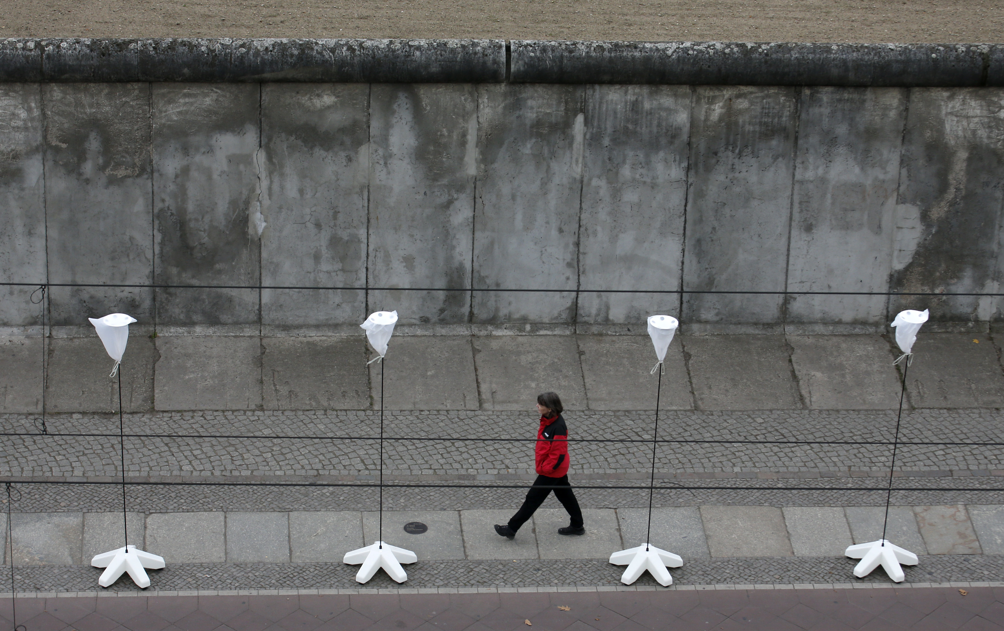A part of the inner city of Berlin will be temporarily divided from November 7 to 9, 2014, with a light installation featuring 8,000 luminous white balloons to commemorate the 25th anniversary of the fall of the Berlin Wall. Here a woman walks in front of A part of the inner city of Berlin will be temporarily divided from November 7 to 9, 2014, with a light installation featuring 8,000 luminous white balloons to commemorate the 25th anniversary of the fall of the Berlin Wall. Here a woman walks in front of
