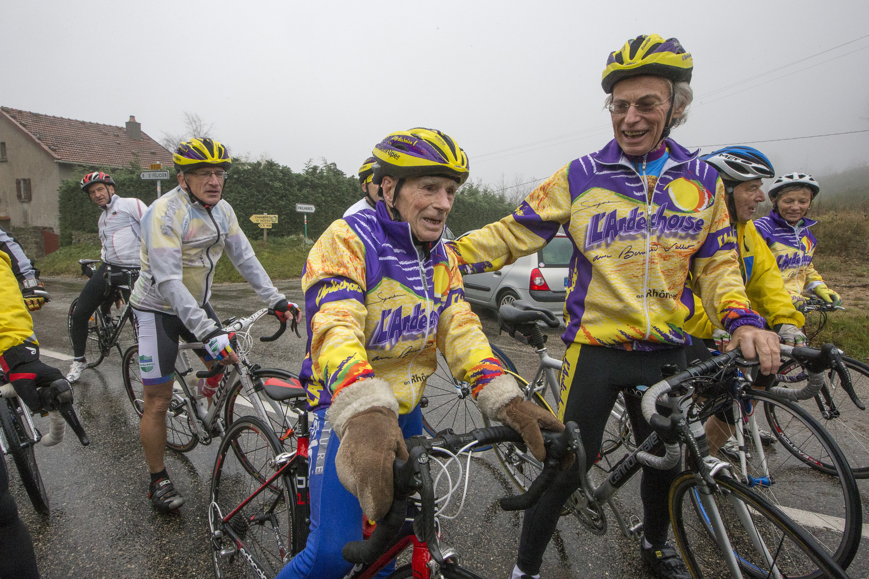 Robert Marchand (C), 103 years-old, speaks with riders as he makes his way along the Robert Marchand pass