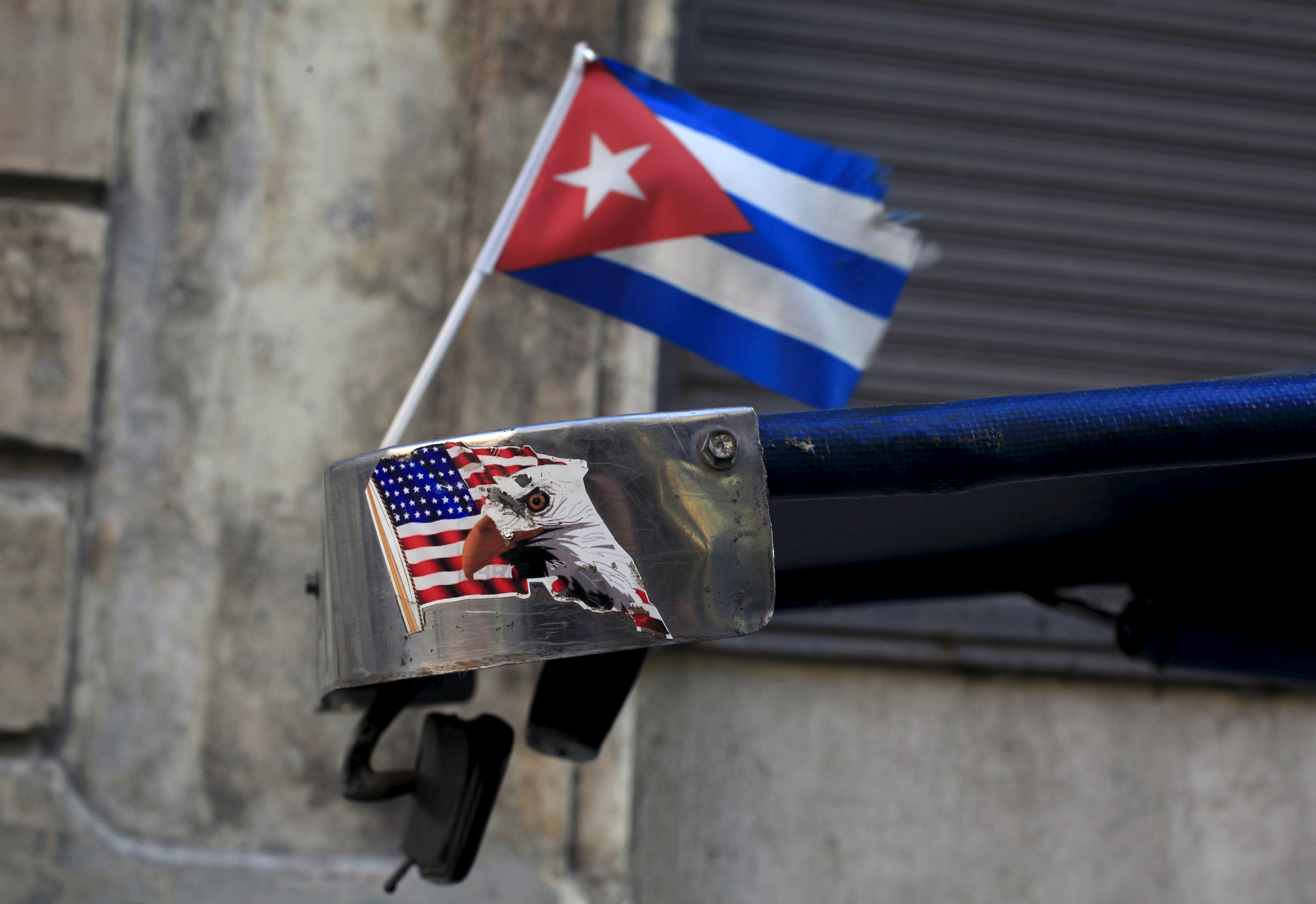 A Cuban flag and a sticker of a U.S. flag are seen on the roof of tricycle taxi in Havana March 9, 2016. A Cuban flag and a sticker of a U.S. flag are seen on the roof of tricycle taxi in Havana March 9, 2016.