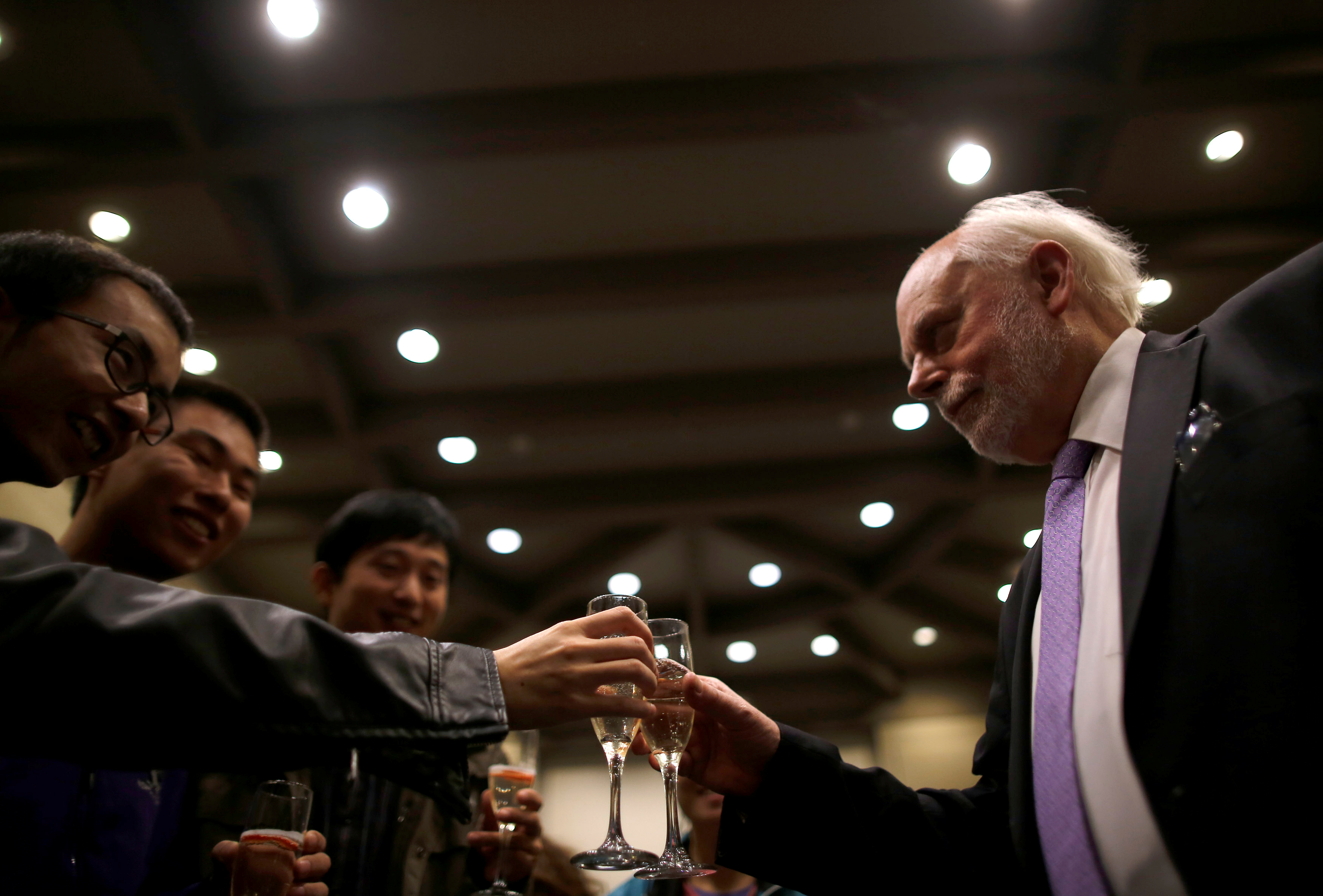 Man with champagne clinks glasses with three other men