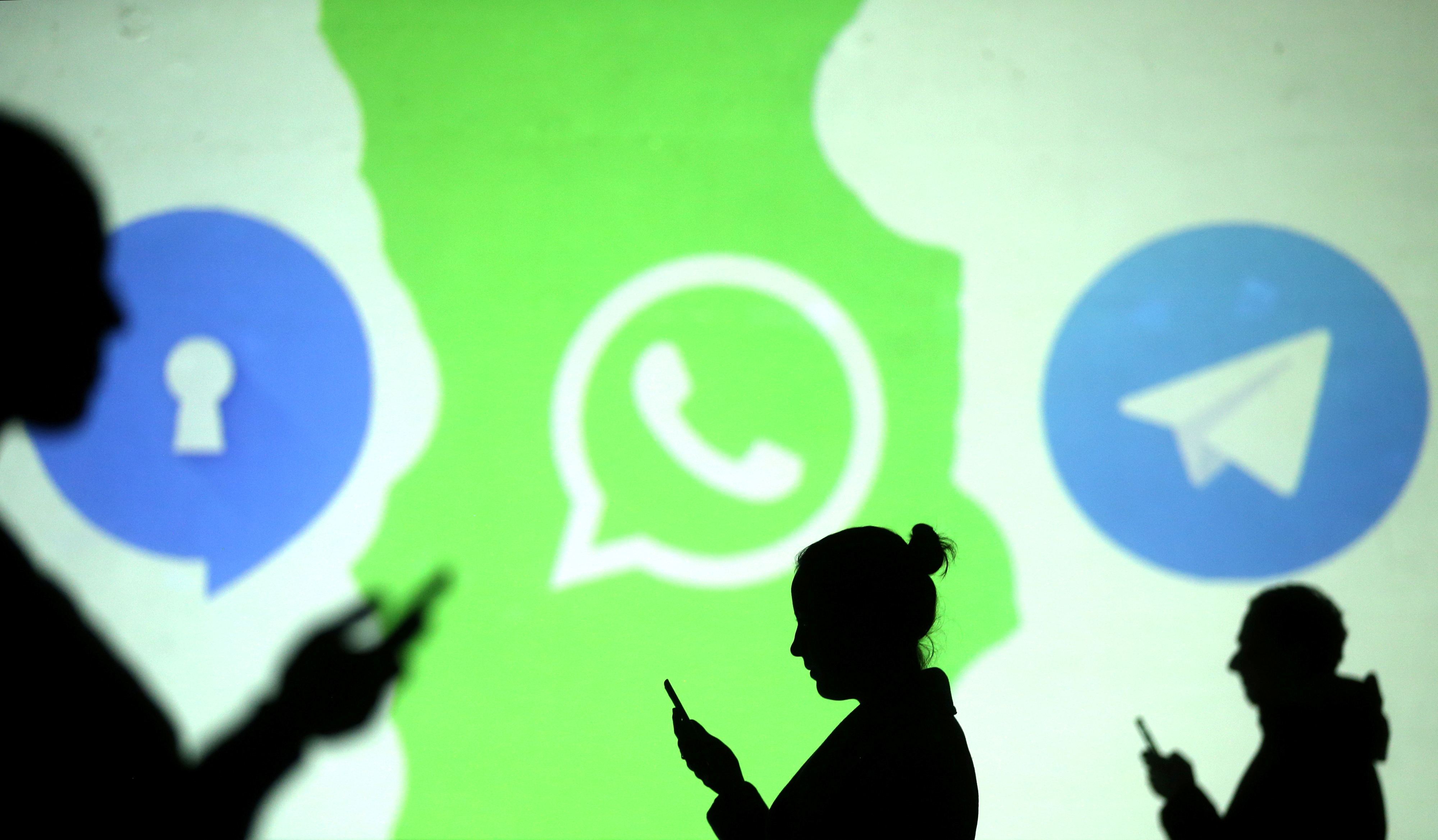 Silhouettes of mobile users are seen next to logos of social media apps Signal, Whatsapp and Telegram projected on a screen in this picture illustration taken March 28, 2018. Silhouettes of mobile users are seen next to logos of social media apps Signal, Whatsapp and Telegram projected on a screen in this picture illustration taken March 28, 2018.