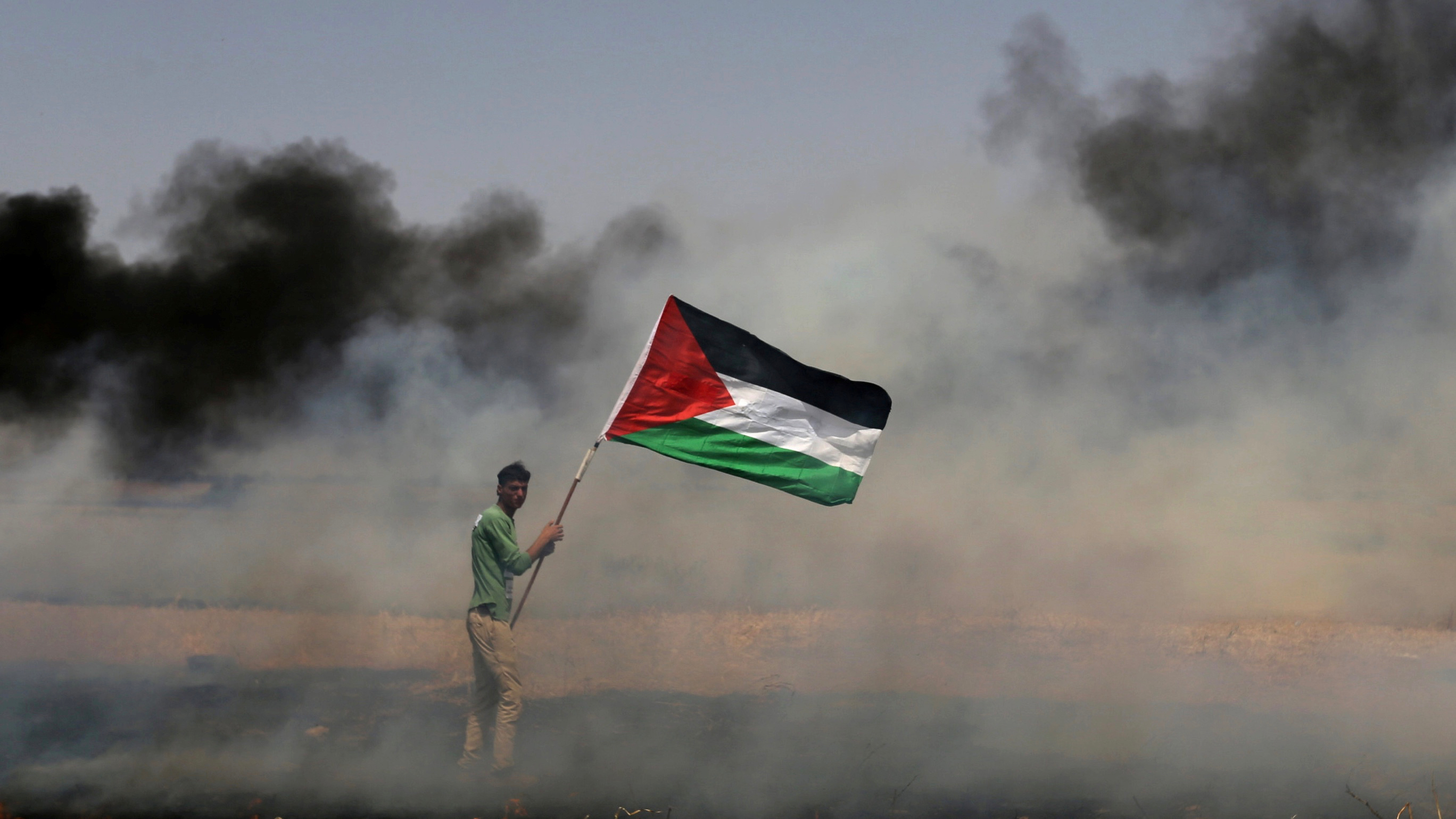 A demonstrator holds a Palestinian flag during clashes with Israeli troops at a protest where Palestinians demand the right to return to their homeland, near the Israel-Gaza border in the southern Gaza Strip on April 13, 2018. A demonstrator holds a Palestinian flag during clashes with Israeli troops at a protest where Palestinians demand the right to return to their homeland, near the Israel-Gaza border in the southern Gaza Strip on April 13, 2018.