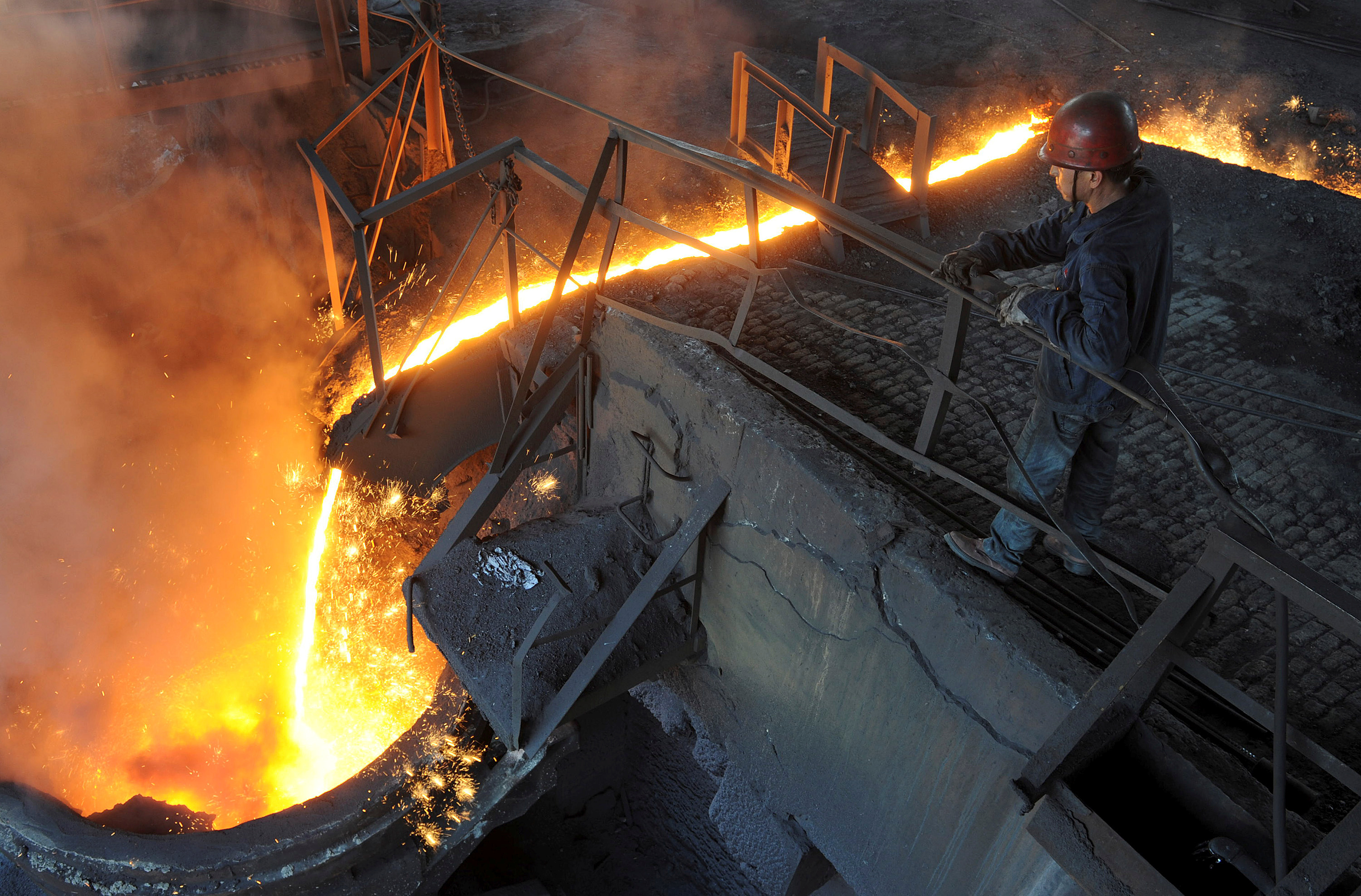 A worker monitors molten iron pouring into a furnace at steel manufacturing plant in Hefei, Anhui province, China. A worker monitors molten iron pouring into a furnace at steel manufacturing plant in Hefei, Anhui province, China.
