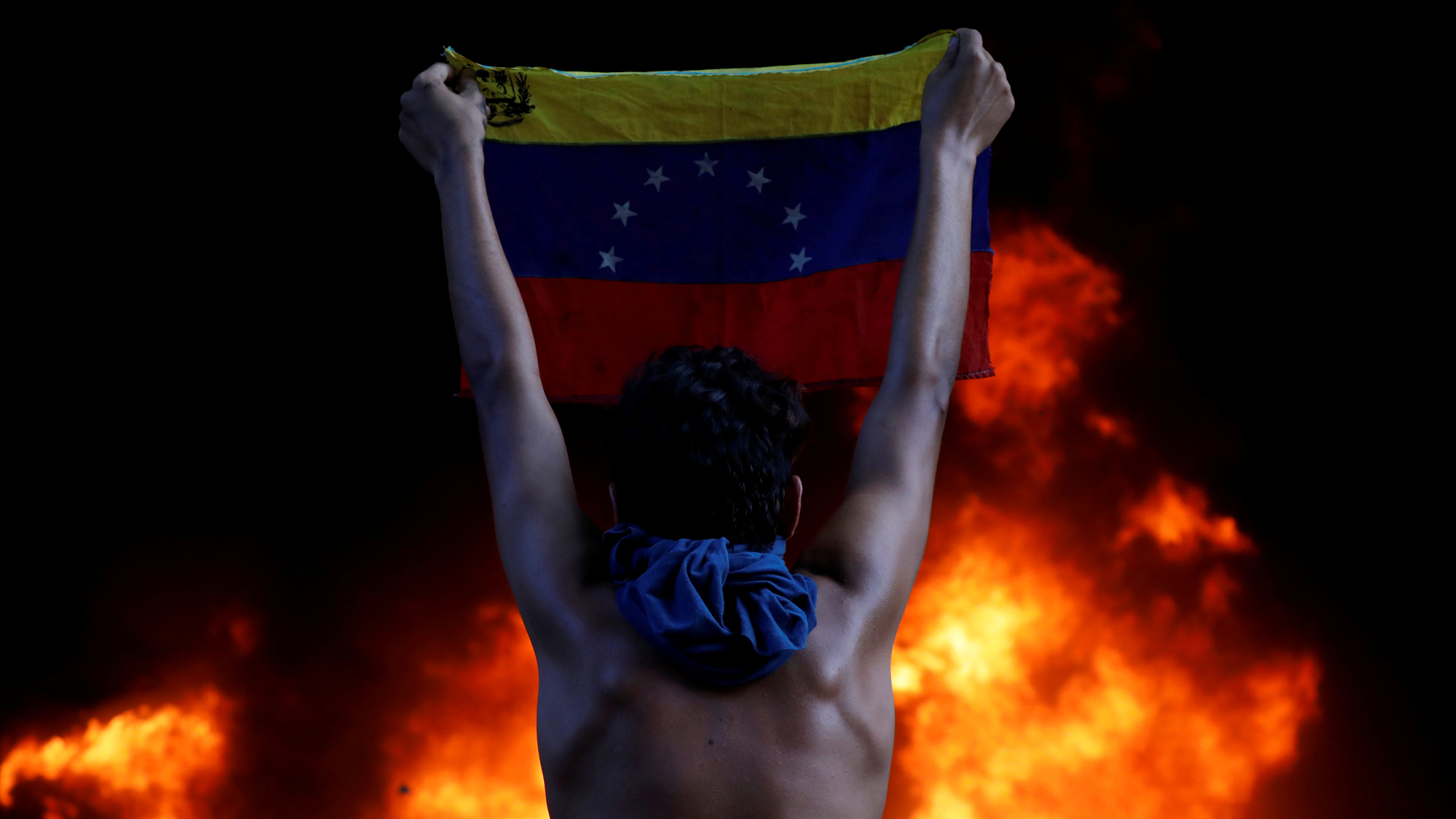 A protester holds a national flag while standing in front of a fire burning at the entrance of a building housing the magistracy of the Supreme Court of Justice, during a rally against Venezuela's President Nicolas Maduro, in Caracas, Venezuela, June 12, A protester holds a national flag while standing in front of a fire burning at the entrance of a building housing the magistracy of the Supreme Court of Justice, during a rally against Venezuela's President Nicolas Maduro, in Caracas, Venezuela, June 12,