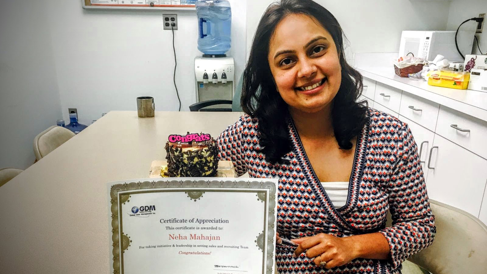 Woman sitting at table holding certificate, smiling