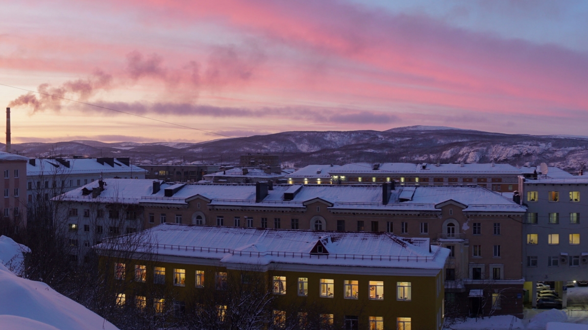 A view of Murmansk, Russia, during the sunrise. It's the first sunrise for Murmansk in 40 days. A view of Murmansk with a smoke stack and other buildings as the sun rises.