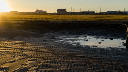 A person walks through a puddle in Shismaref, Alaska.